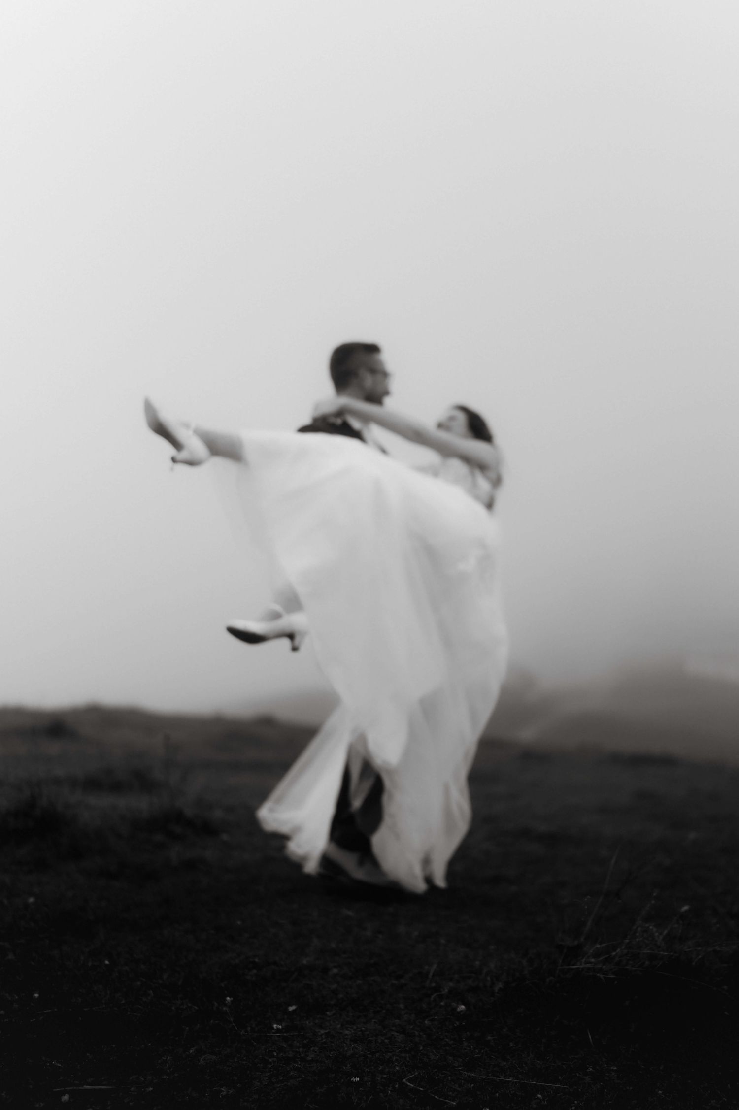 Stimmungsvolles Schwarzweißfoto von Dina & Sebastian im Nebel auf einem Berg in Vorarlberg – cineastisches Hochzeitsbild voller Emotion.