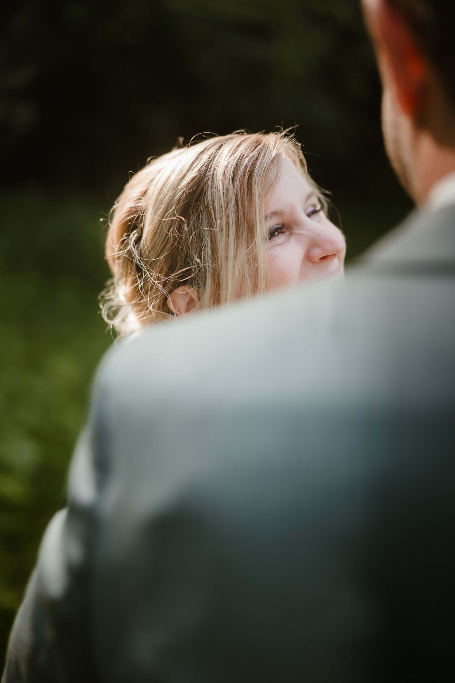 Die Braut strahlt ihren Bräutigam mit Glück an – natürliche Hochzeitsfotografie in Vorarlberg von NuMa Fotografie.