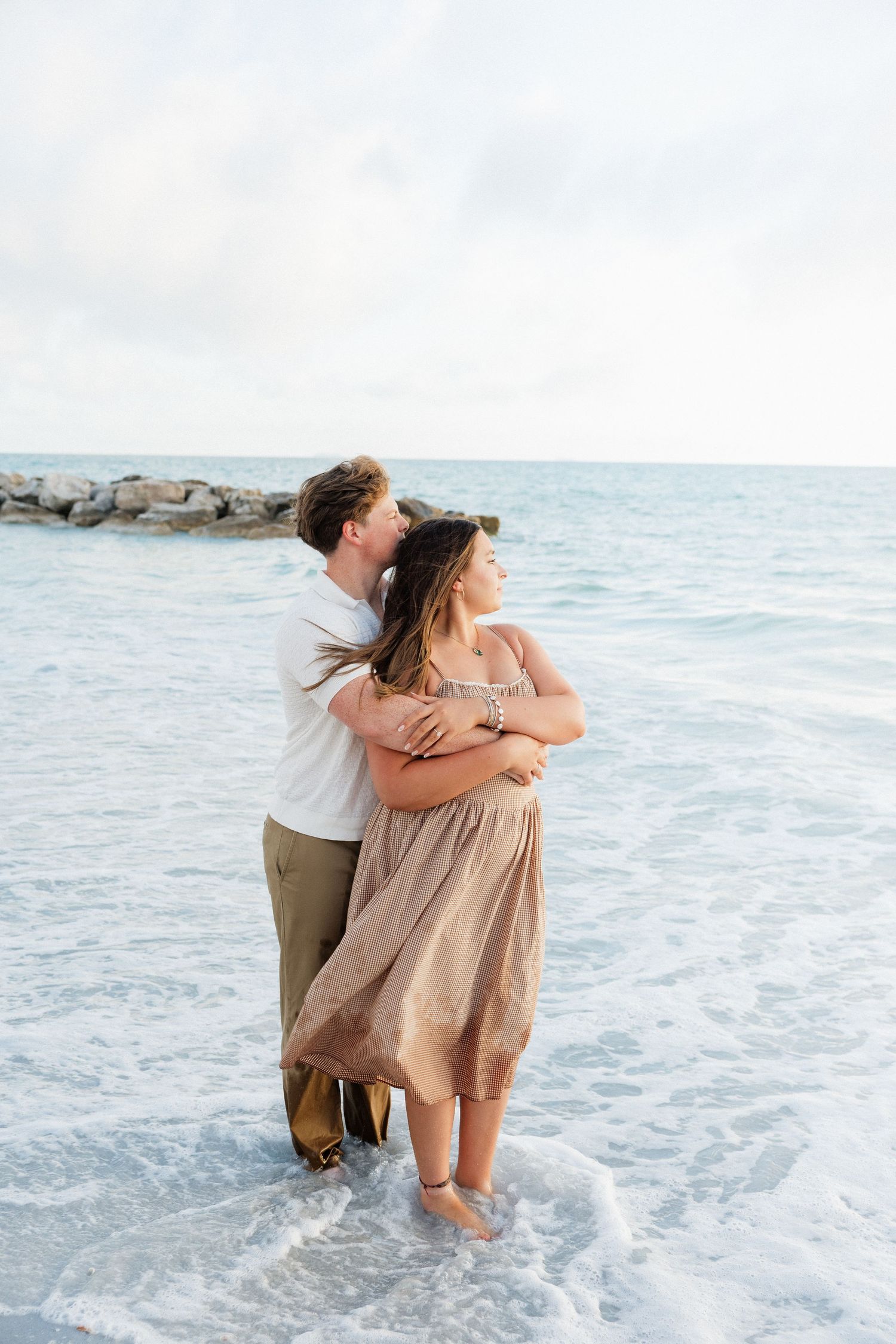 Couple embracing in the ocean during a sunset engagement session at Honeymoon Island near Tampa Bay.