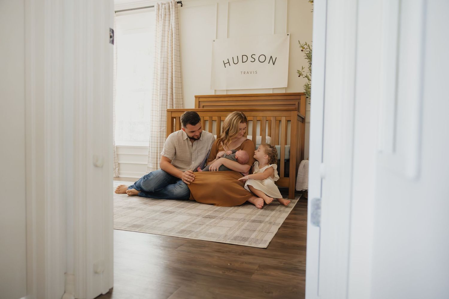 Lifestyle newborn photography of family cuddling together in a cozy nursery.