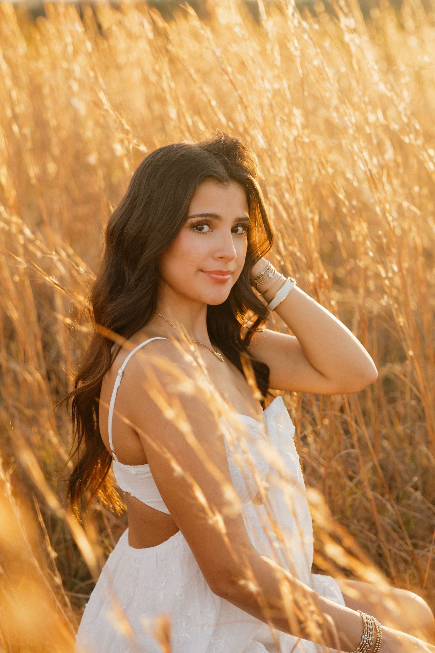 Florida senior portrait in a white dress photographed in a golden field at sunset.