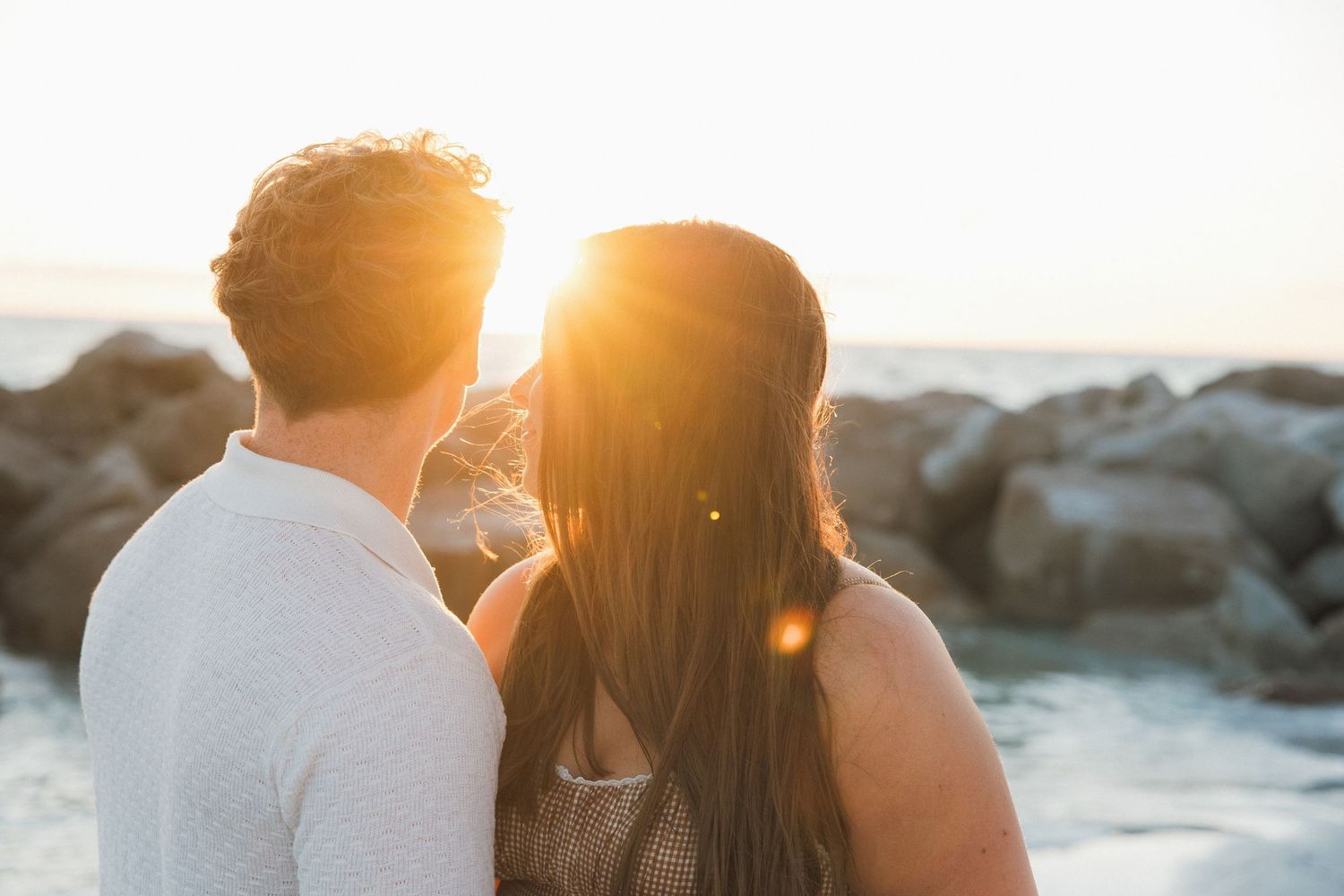 Honeymoon Island engagement session with couple watching the sunset on the rocky shoreline.