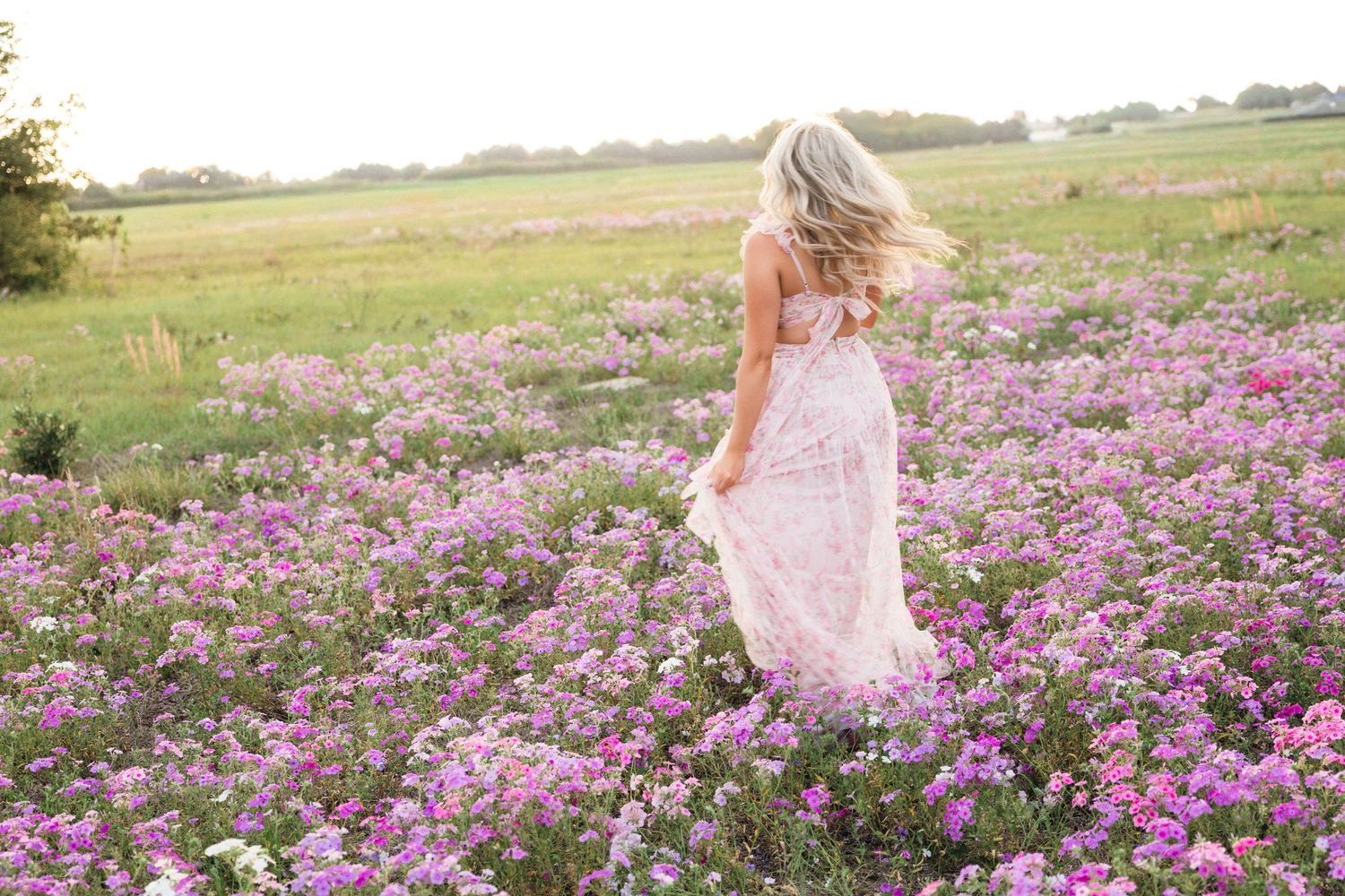Senior portrait in a pink floral dress in a Florida wildflower field at golden hour.
