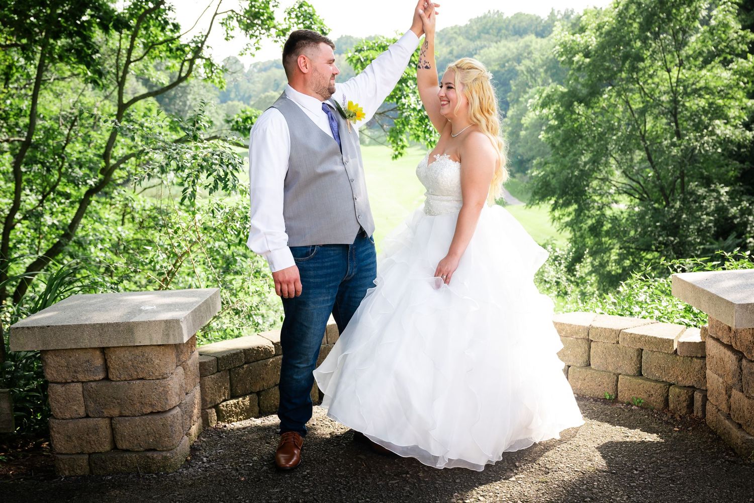 A couple celebrates their wedding day dancing on a stone terrace surrounded by lush greenery.