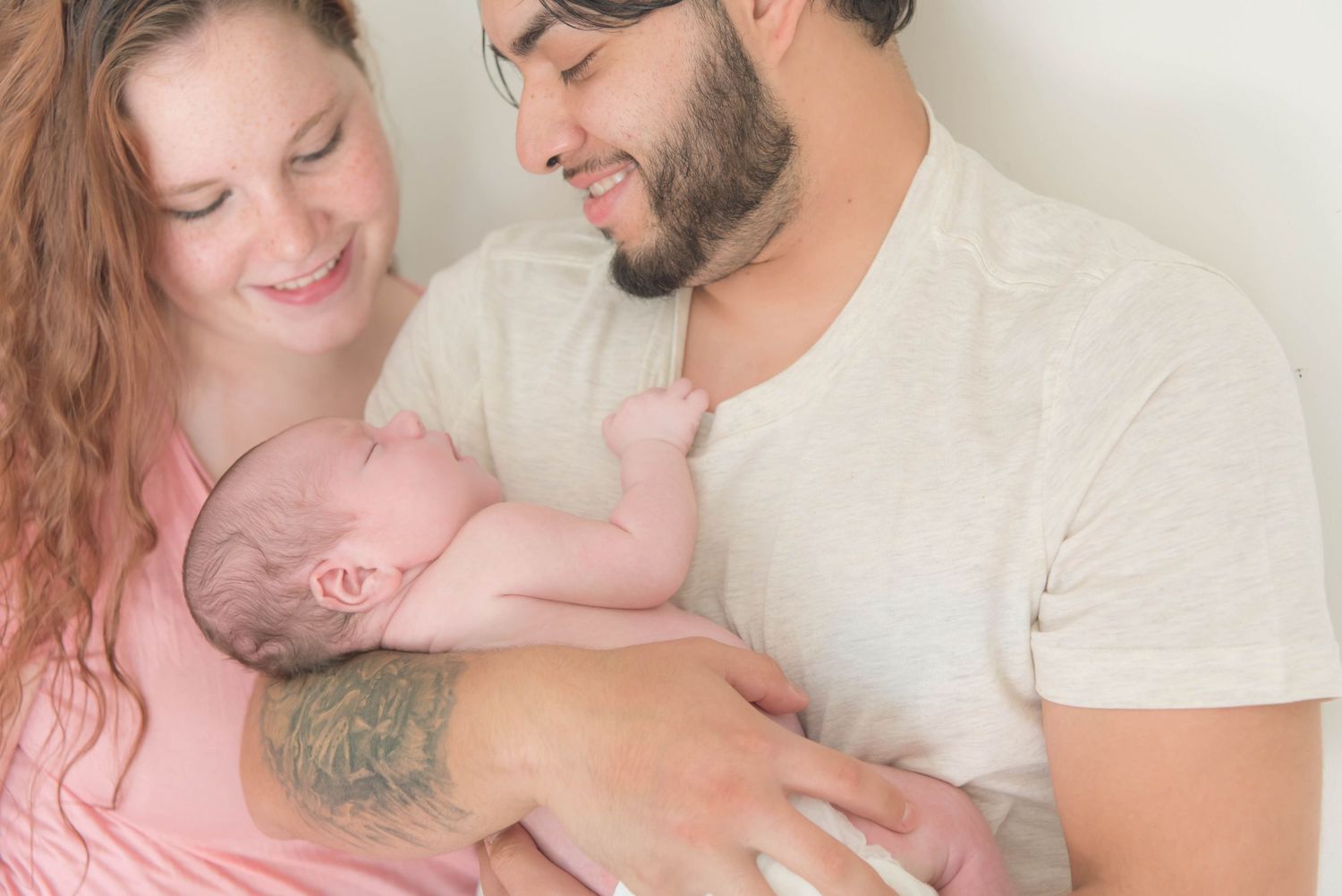 A tender family moment captured in soft lighting with people in pink and white clothing embracing.