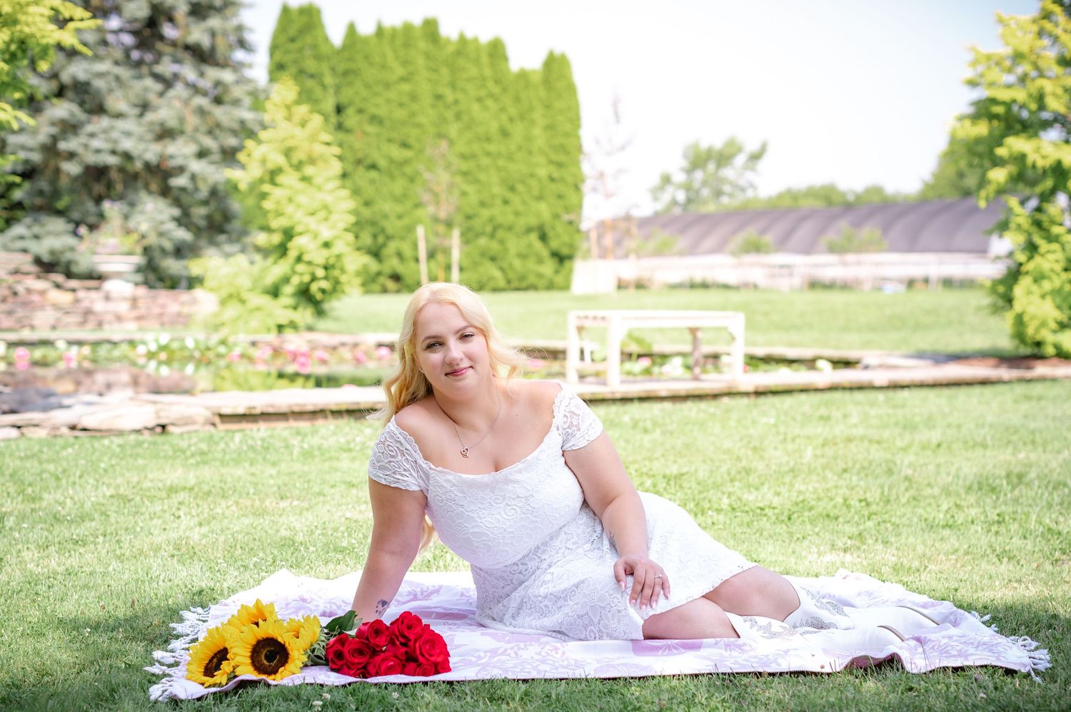 An elegant garden portrait with sunflowers and roses on a white blanket.