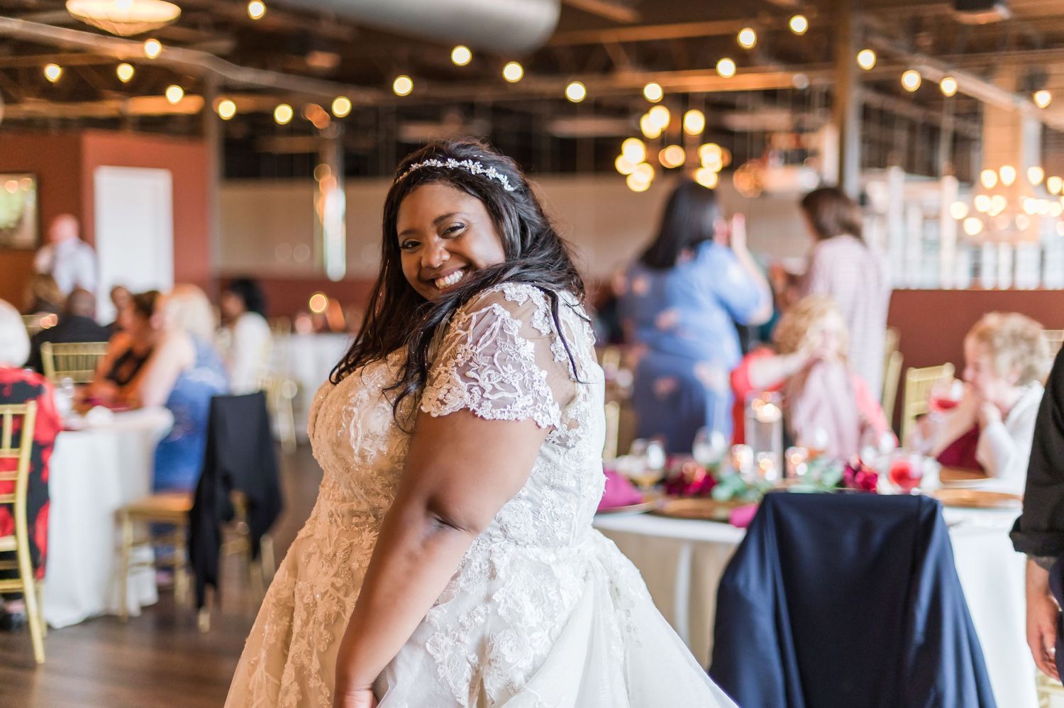 Bride in white lace dress smiling during wedding reception.