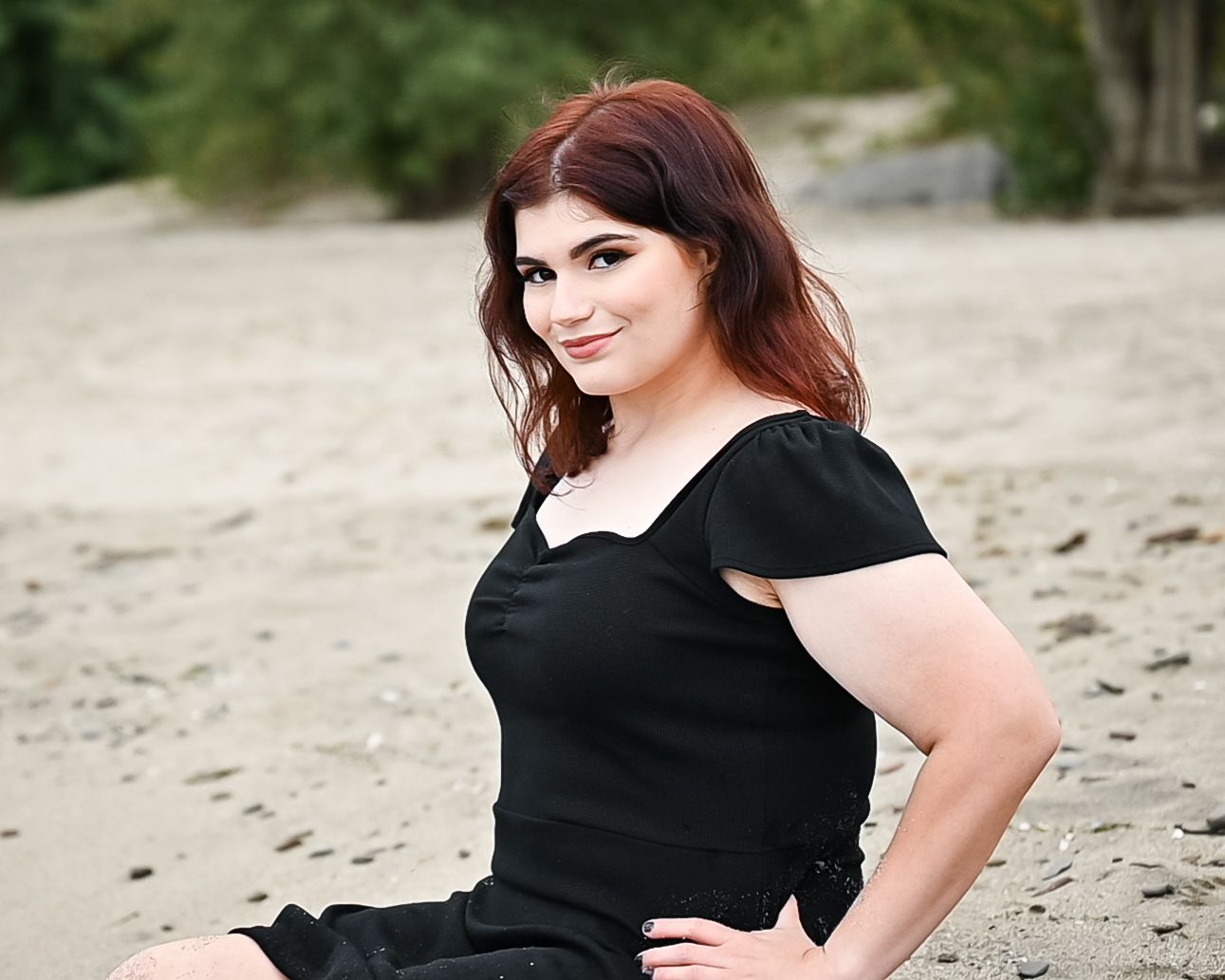 Portrait session on a beach wearing a classic black dress.
