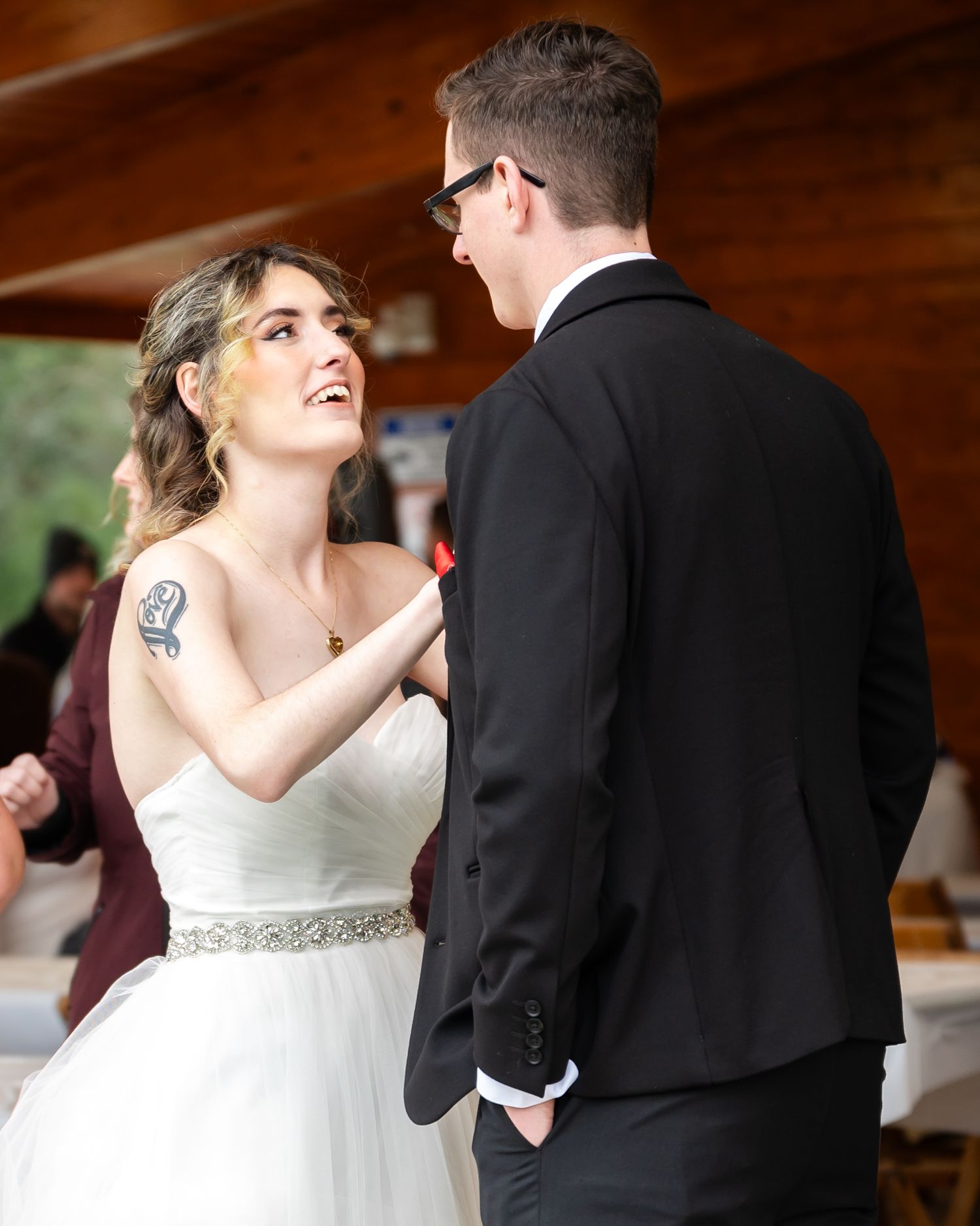 A couple shares a joyful moment during their wedding dance, with the bride in a white gown with crystal belt.