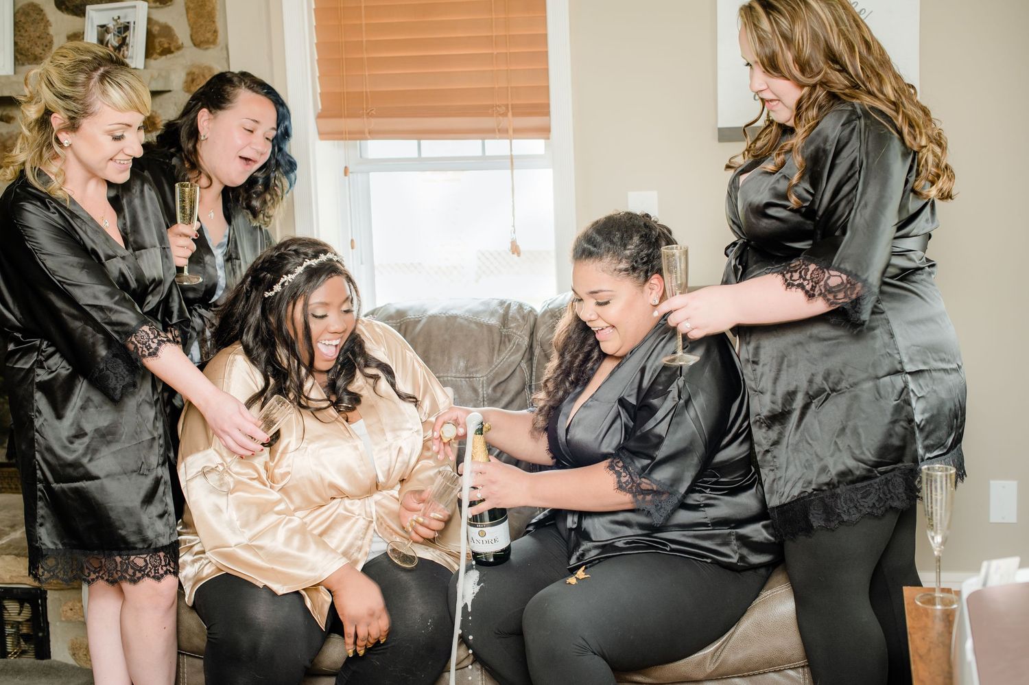 Wedding party in matching robes celebrates with enthusiasm during morning preparations.