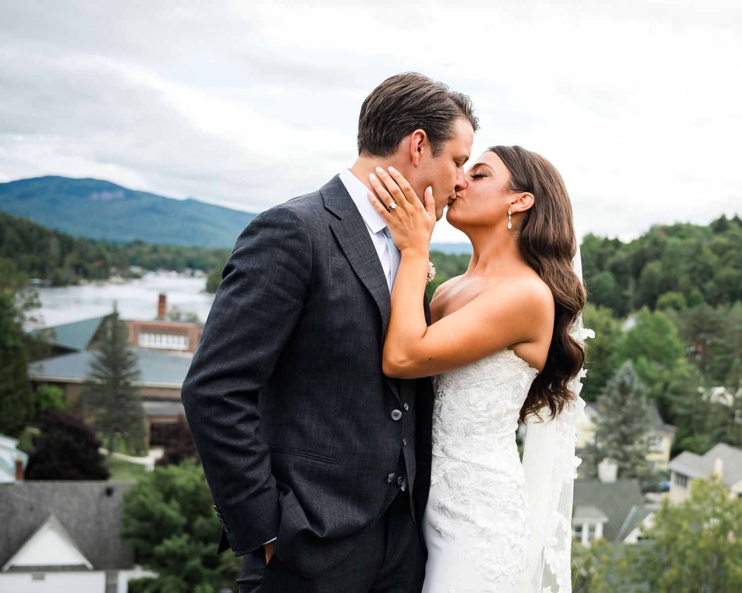 A romantic wedding portrait with a scenic mountain vista and town backdrop.