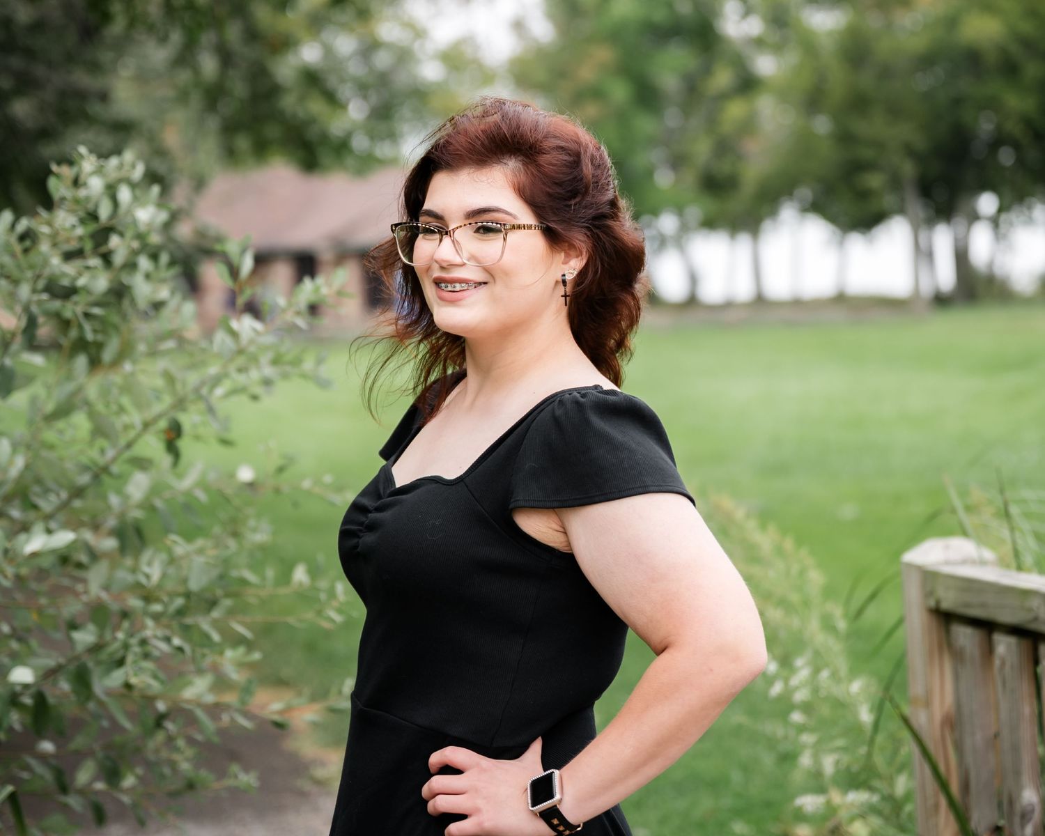 Outdoor portrait in a park setting wearing a black dress with sweetheart neckline.