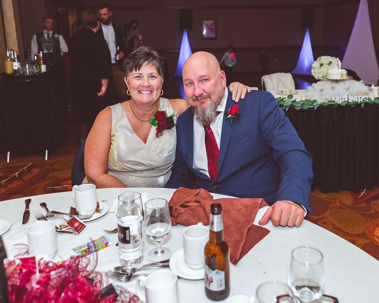Wedding reception guests enjoying dinner and drinks at decorated banquet table.
