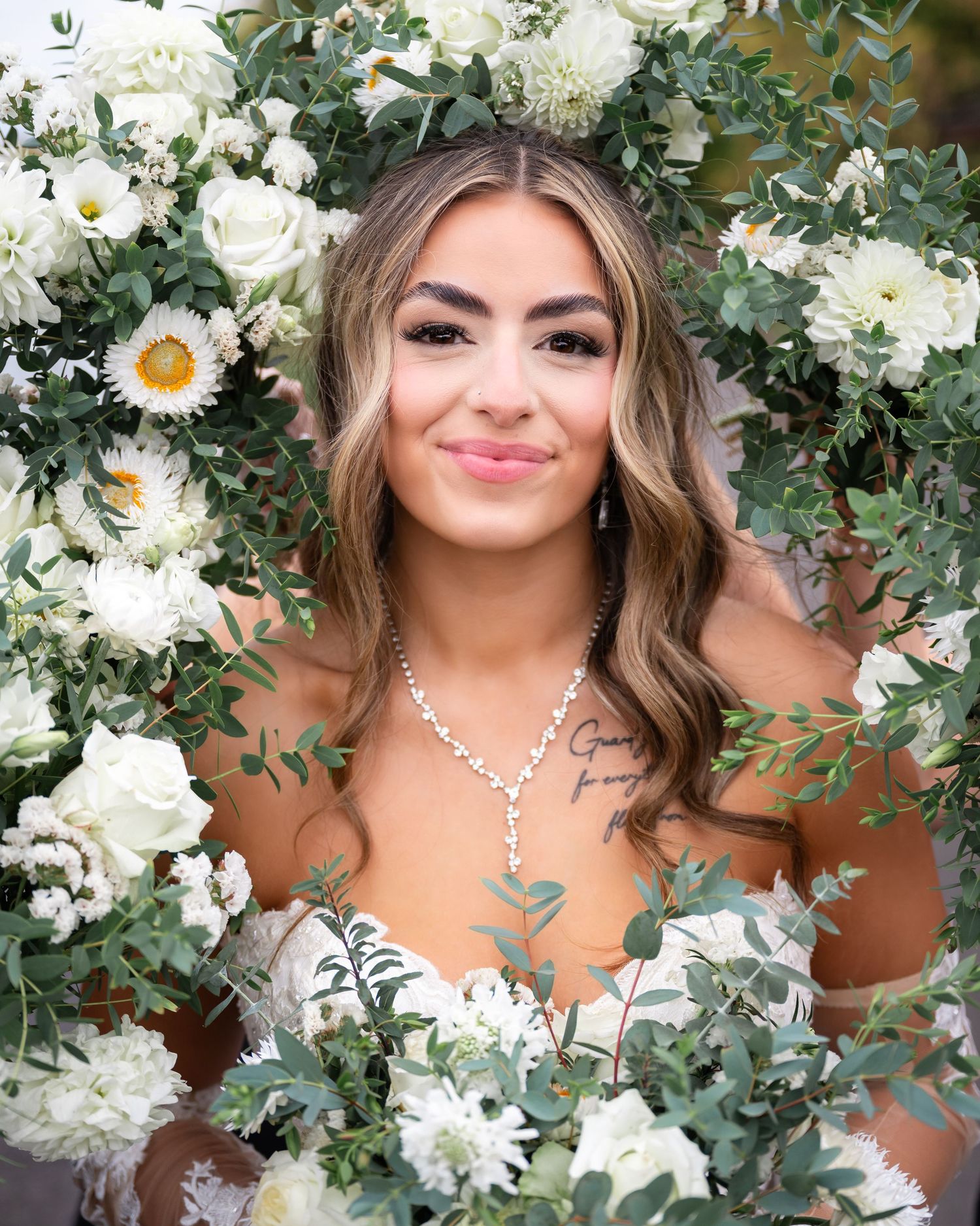Beautiful bridal portrait surrounded by white roses, daisies and greenery in an elegant floral frame arrangement.