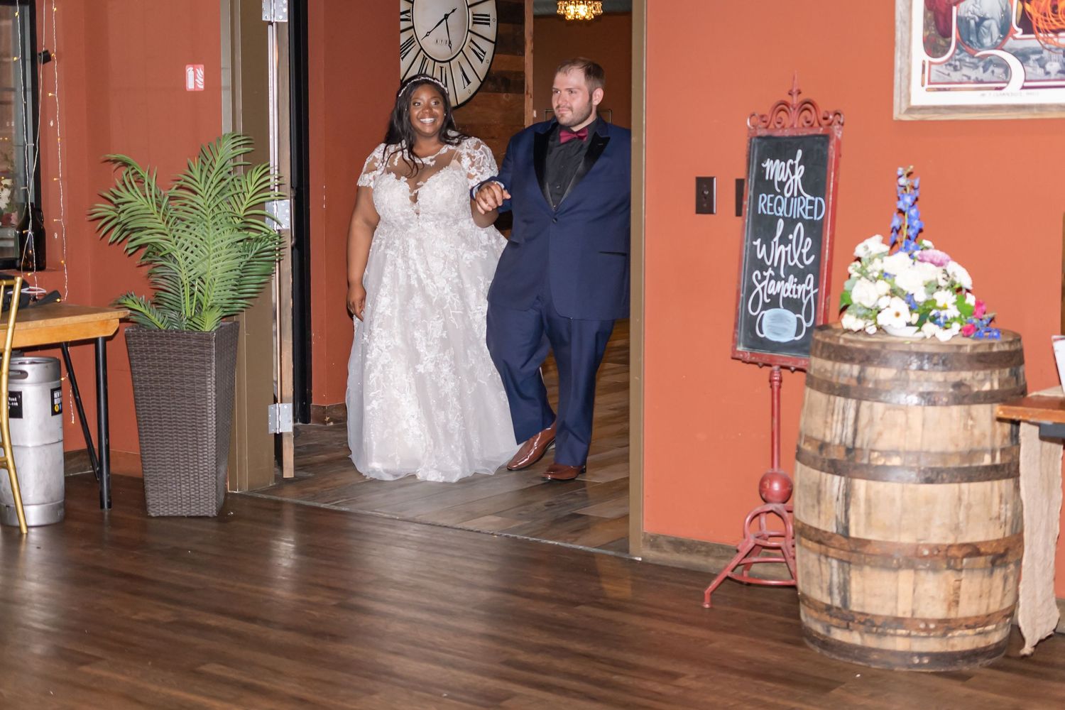 A wedding couple makes their grand entrance through wooden doors at their reception venue.