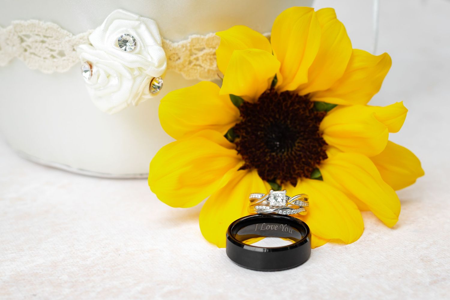 Wedding ring displayed on bright yellow sunflower with white lace detail.