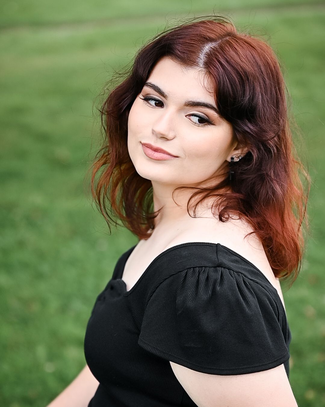 Elegant portrait in black off-shoulder dress with natural makeup and styled auburn hair.