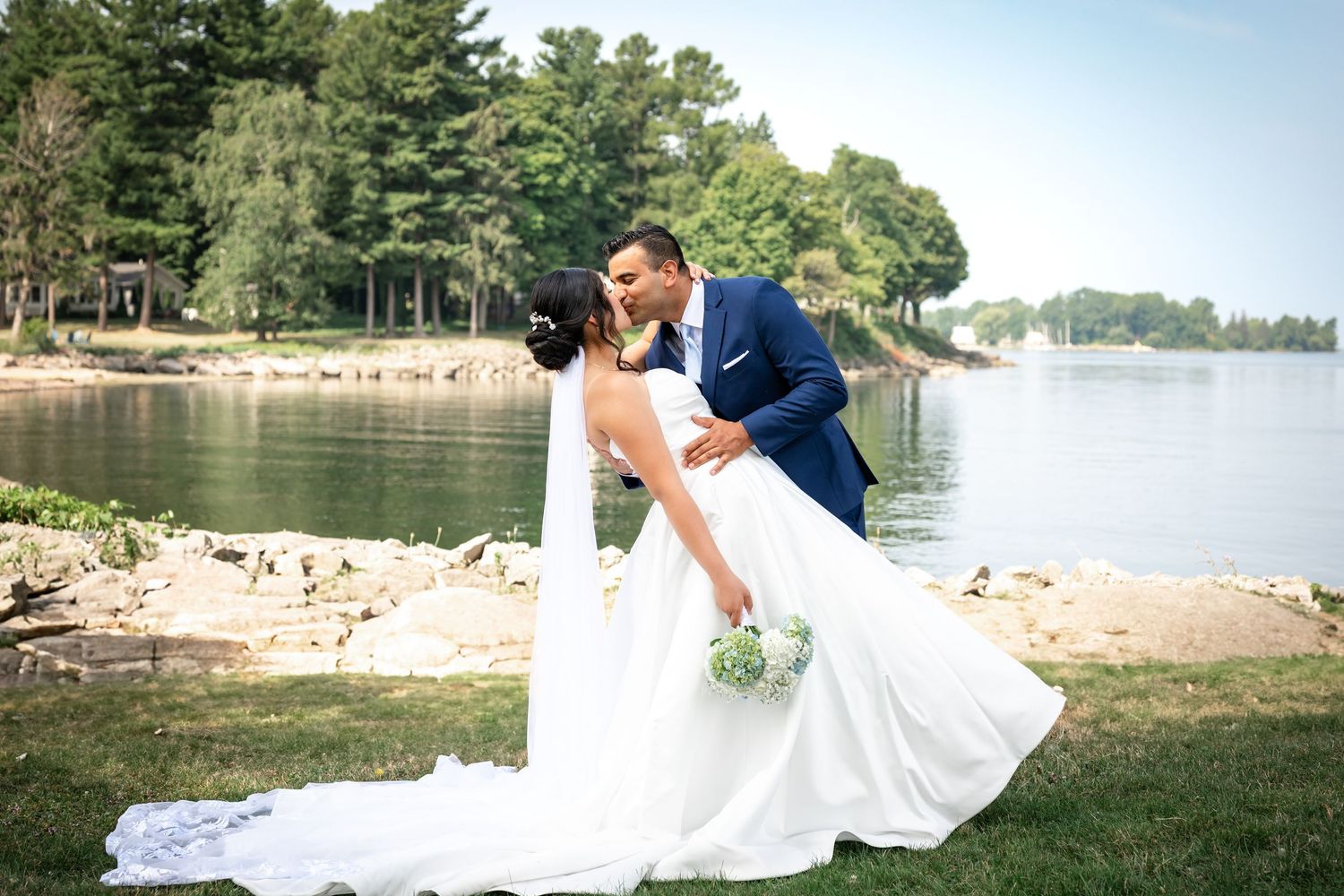 A romantic lakeside wedding photo session with a couple posing near the water's edge at sunset.