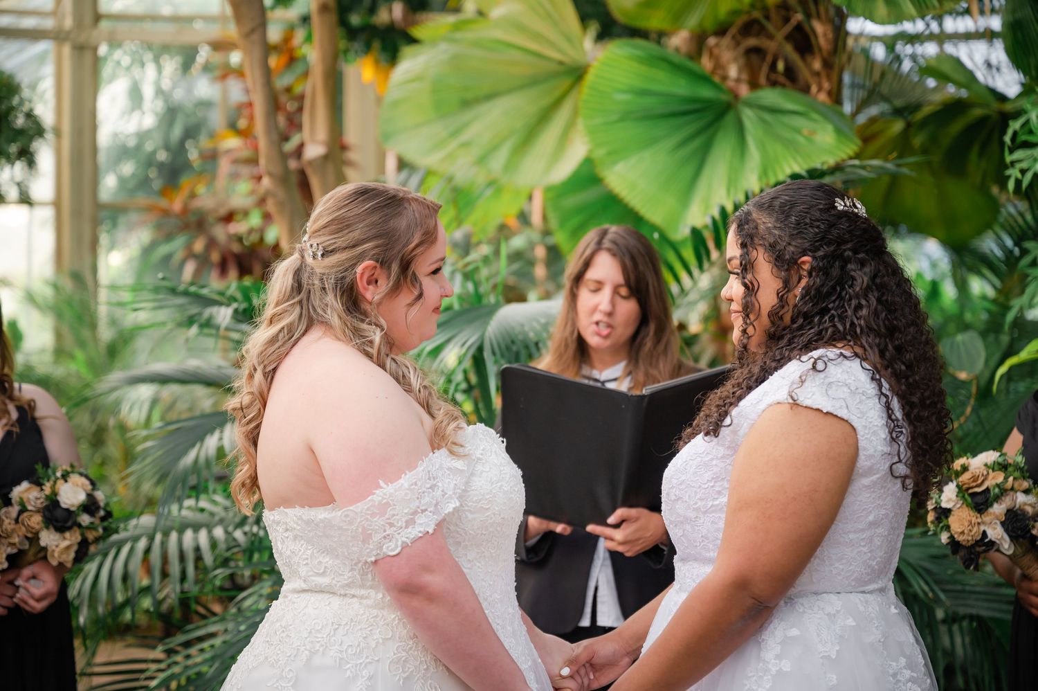 Wedding ceremony in a tropical greenhouse with officiant reading from book.