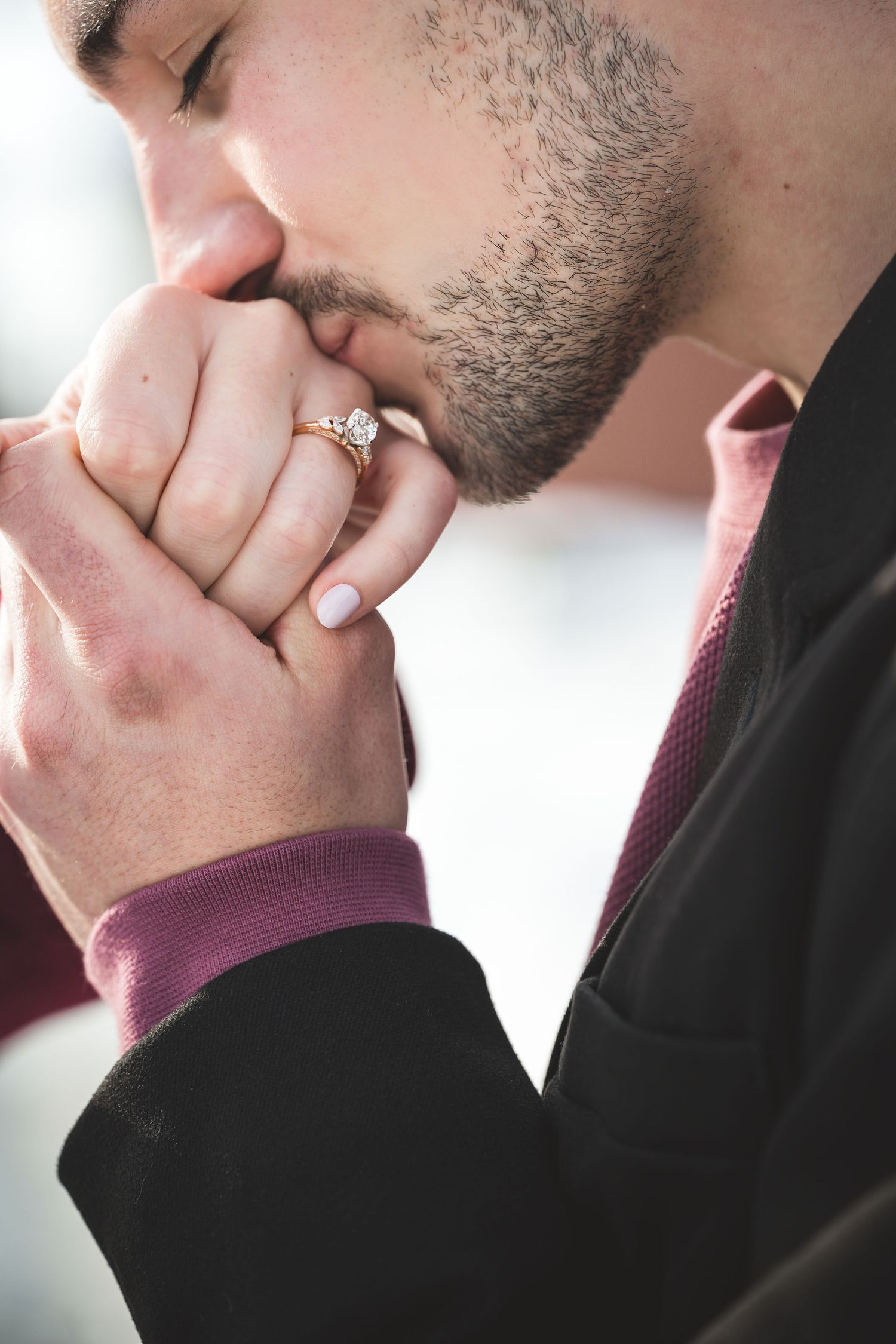 Close-up view of a couple's hands showing an engagement ring with soft lighting and romantic atmosphere.