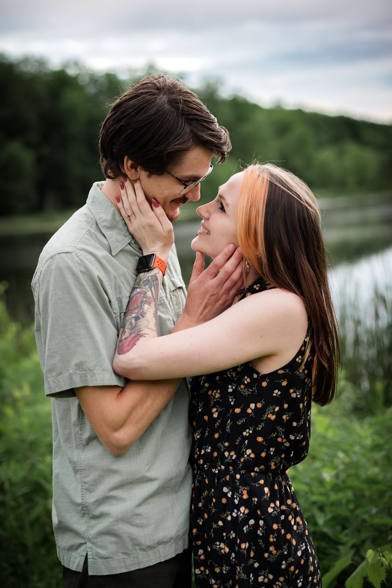Tender moment shared between couple in floral dress and casual shirt by lakeside.