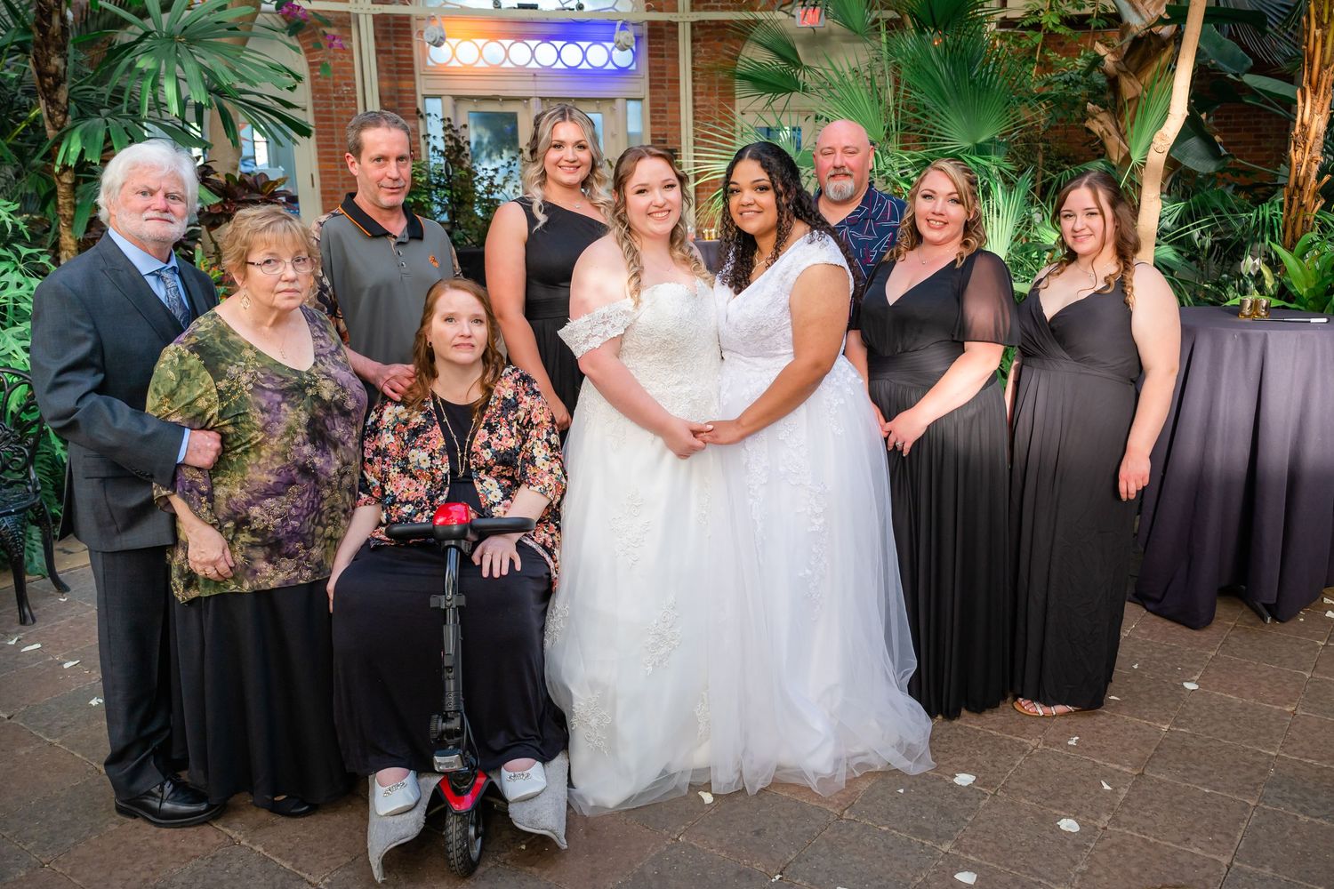 Wedding party poses together in front of tropical garden backdrop with illuminated archway.