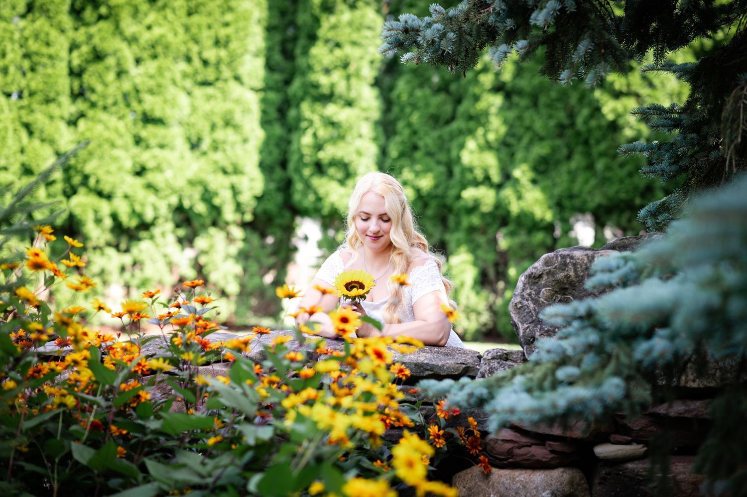 A stone-edged garden overflows with bright orange and yellow summer blooms.