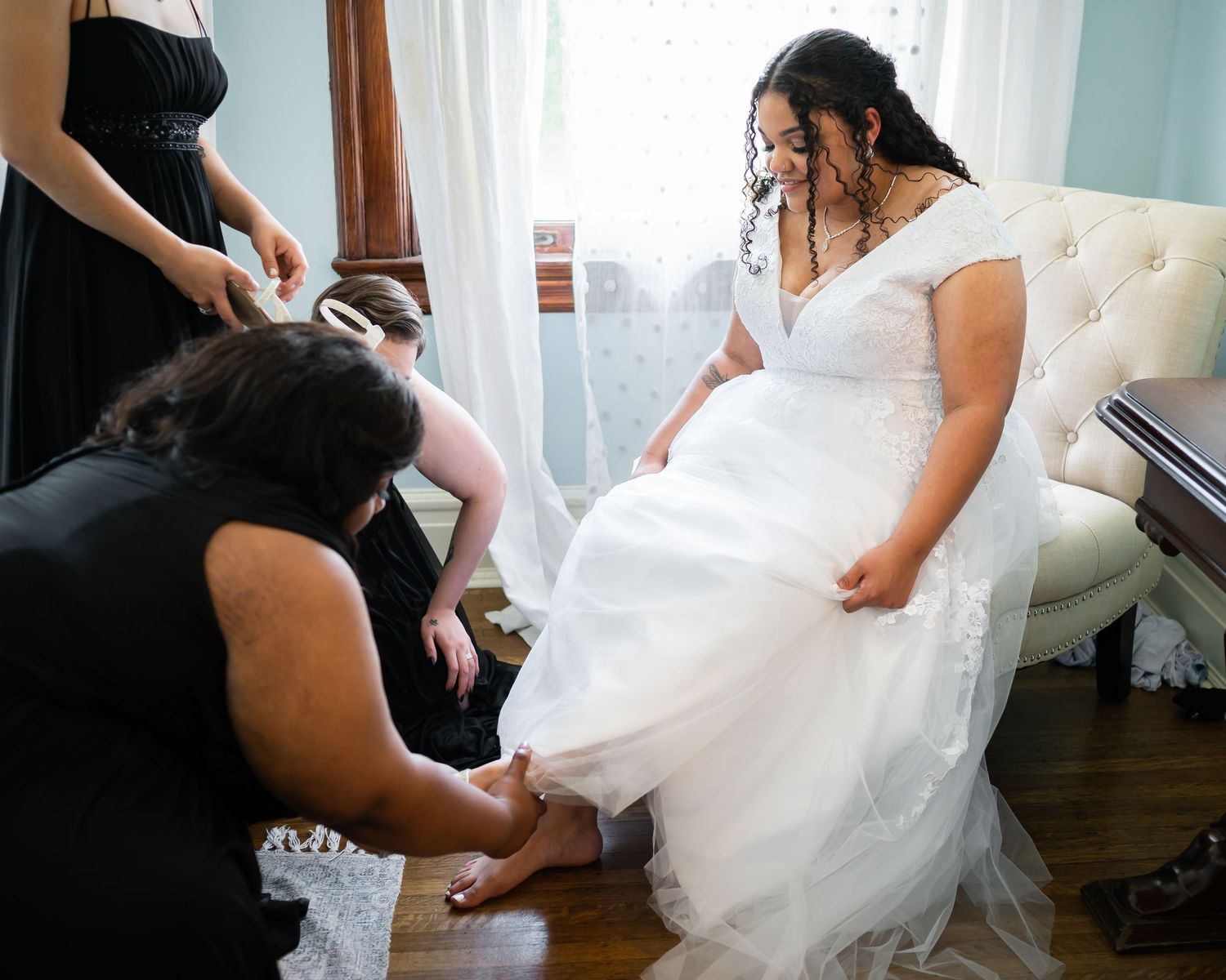 Wedding dress preparations with attendants helping with final touches.