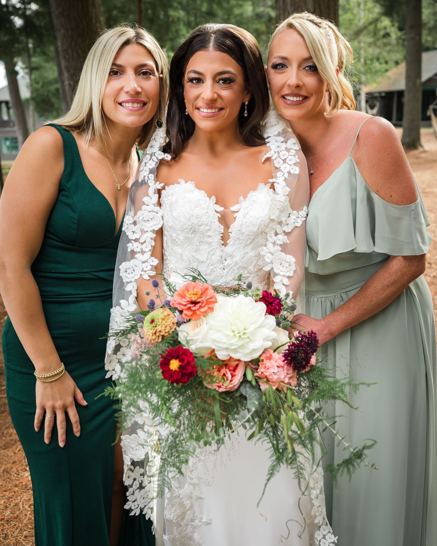 Bridesmaids in jewel-toned dresses pose with colorful bouquet outdoors.
