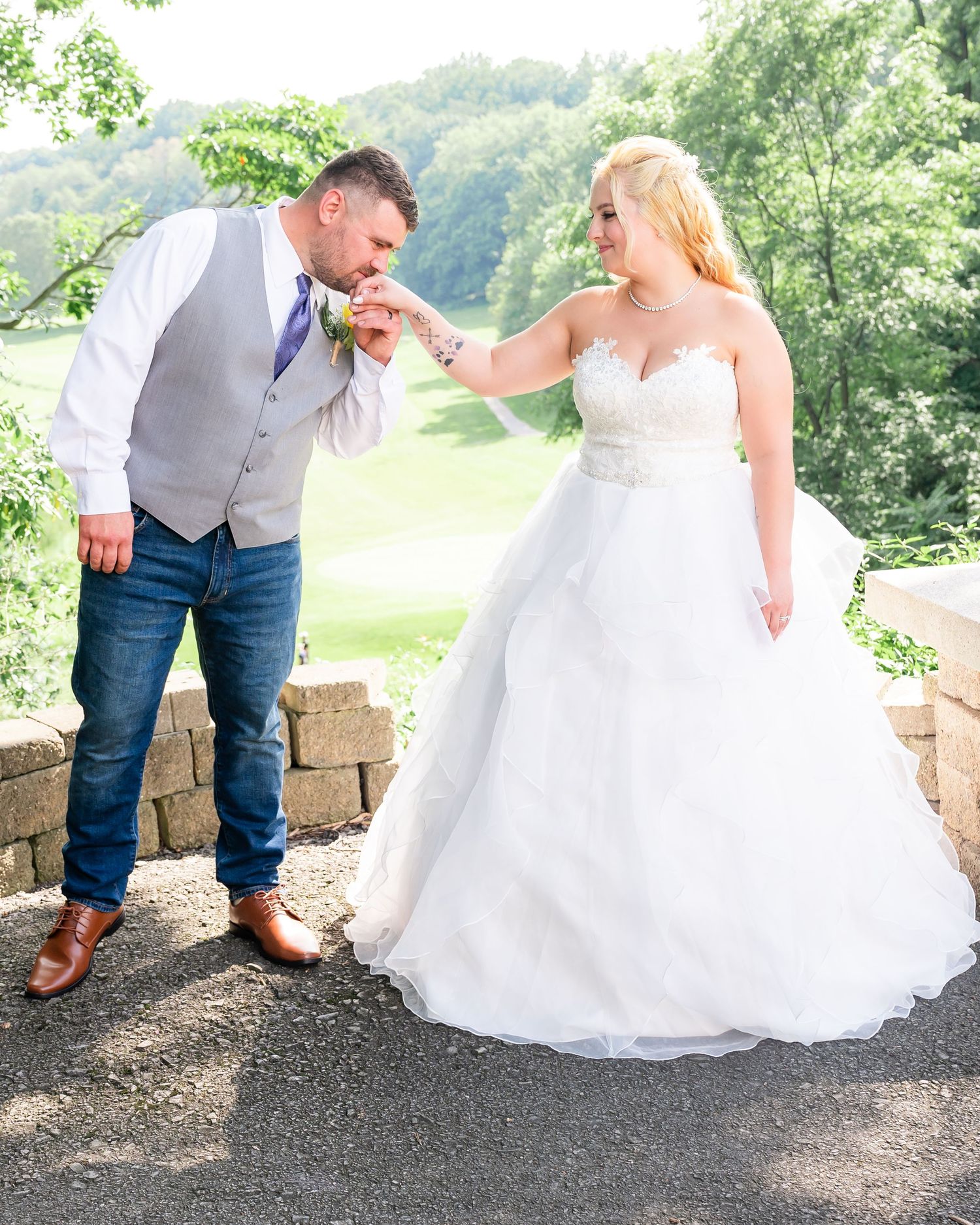 Playful wedding moment captured on stone overlook with scenic background.