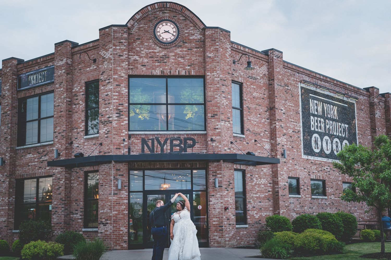 Brick building exterior with newlyweds standing at entrance.