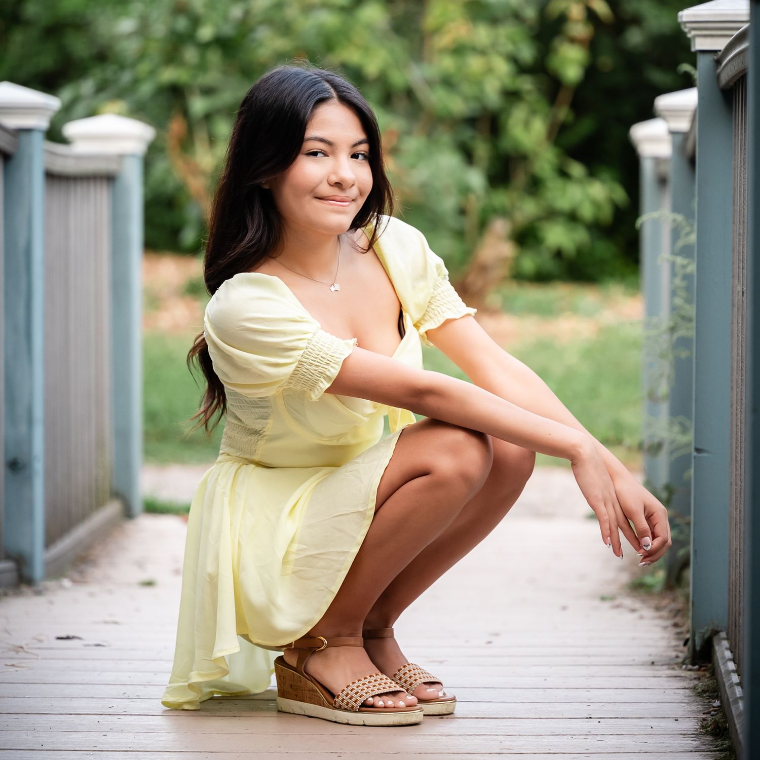 Yellow sundress and sandals worn in a casual outdoor garden photoshoot.