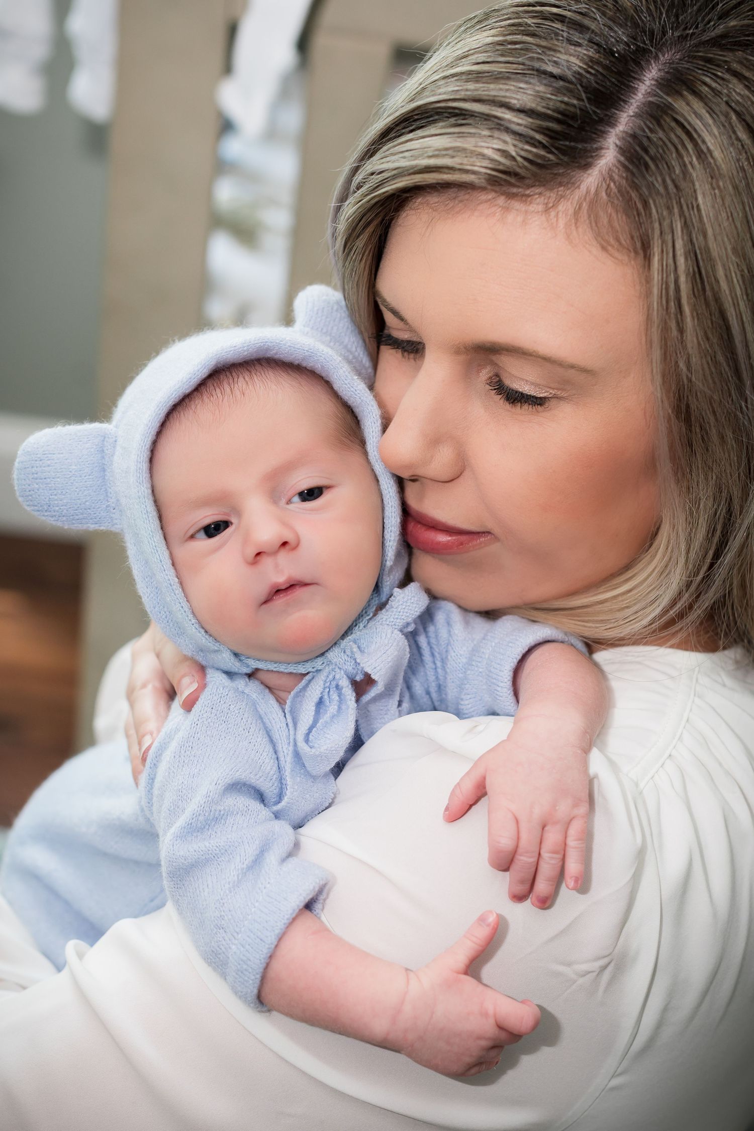 A tender moment between parent and baby in soft lighting shows gentle affection and bonding.