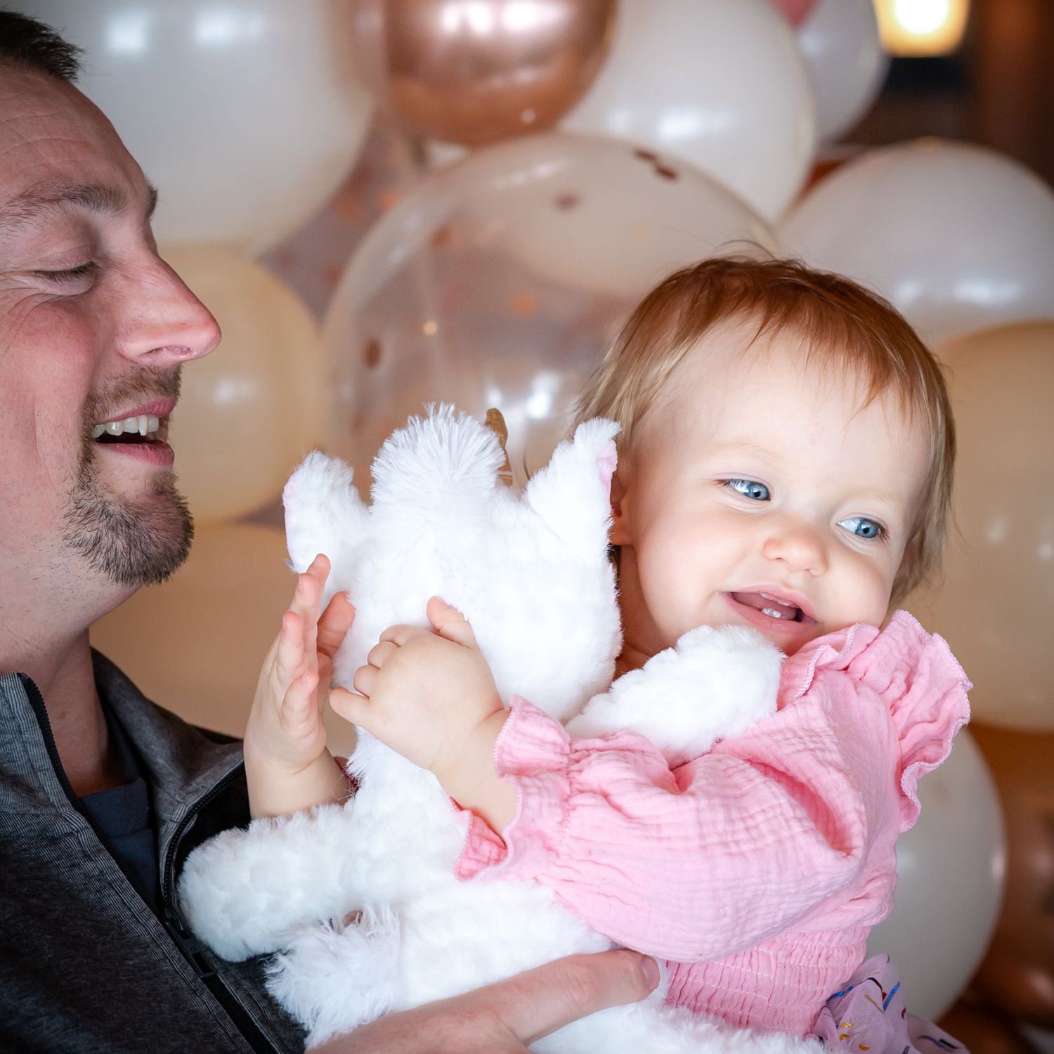 A baby in pink clothing plays with a fluffy white teddy bear in a heartwarming sequence of candid moments.