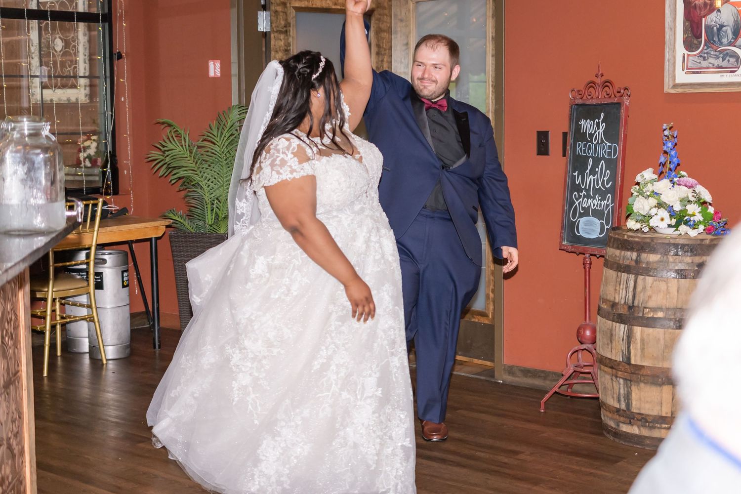 A joyful first dance between newlyweds at a rustic indoor wedding venue with warm lighting and decor.