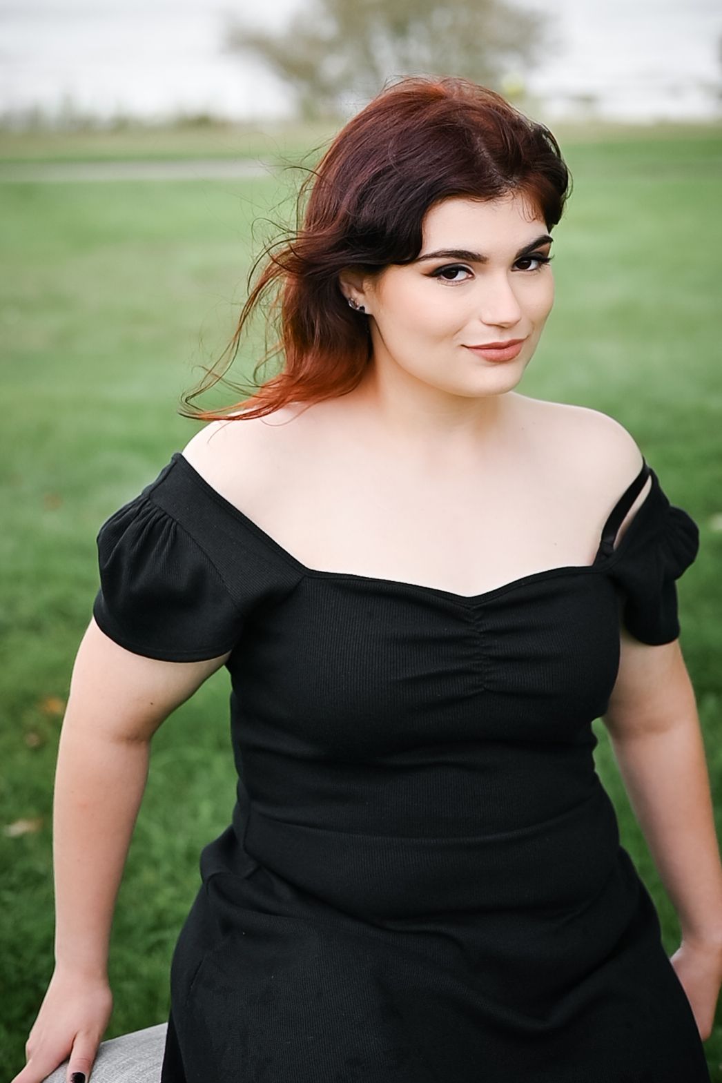 A black dress with puff sleeves photographed outdoors in a natural setting.