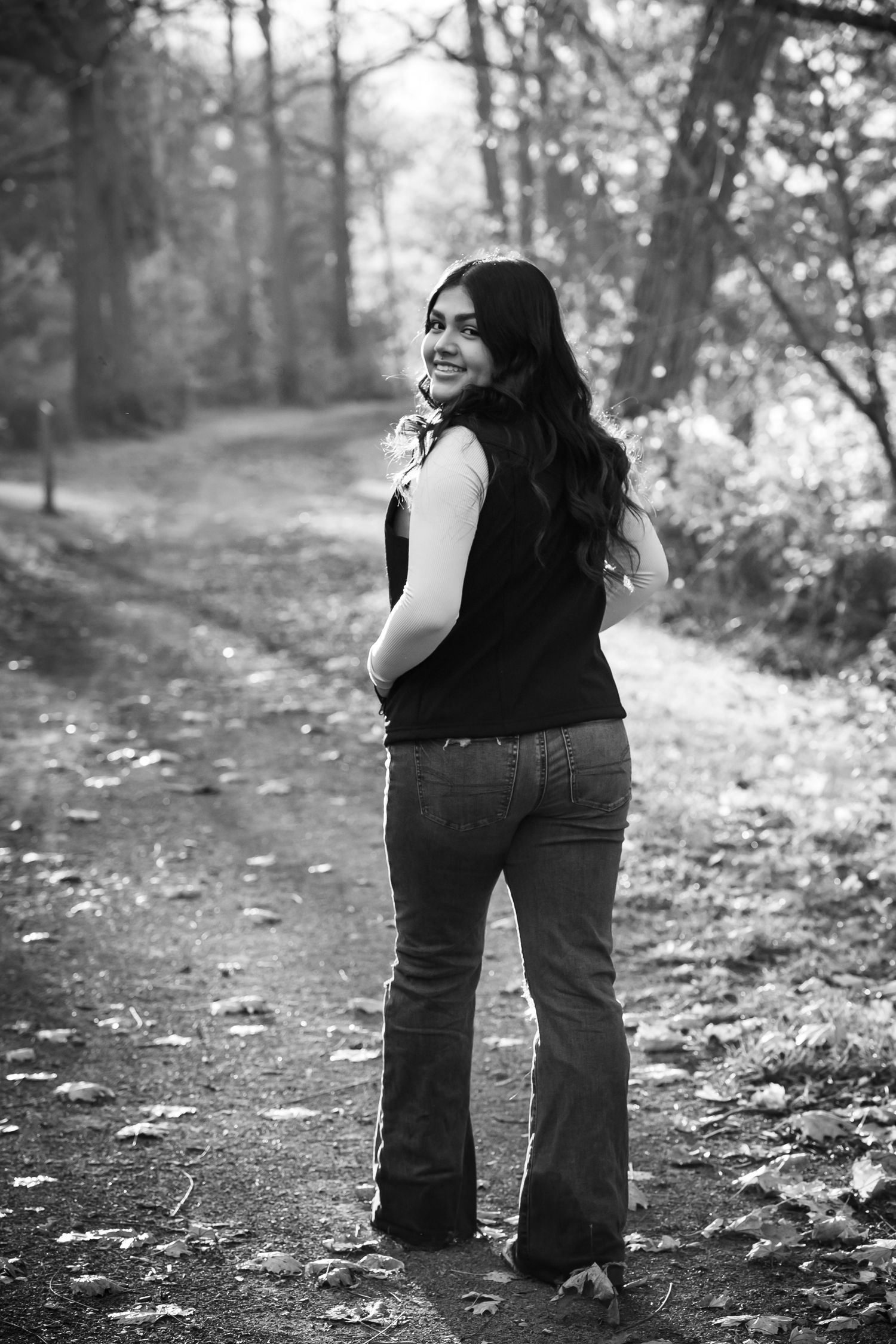 A black and white photo sequence shows a person walking along a leaf-covered forest path on an autumn day.