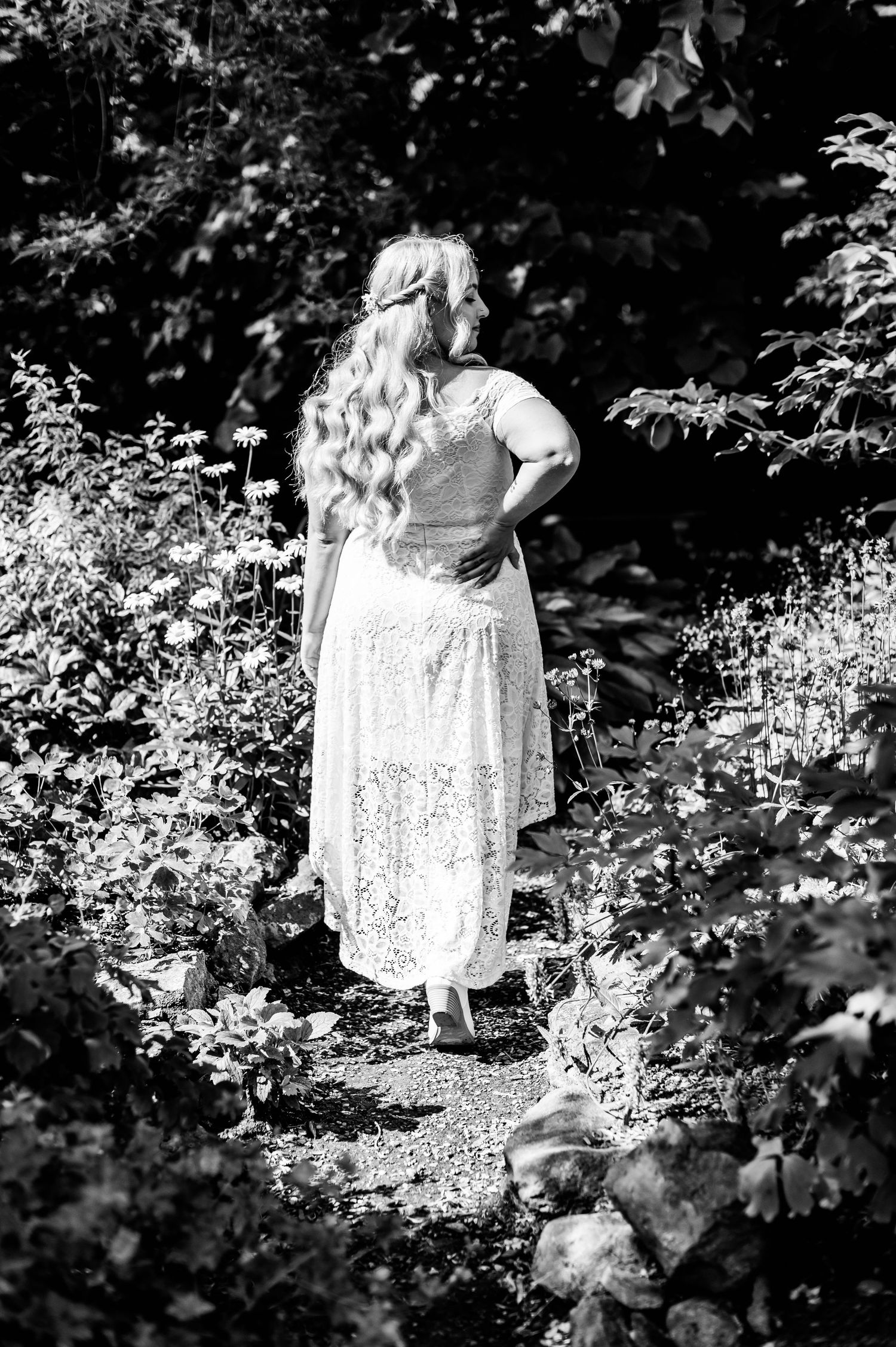 Black and white portrait shows a delicate lace dress among garden pathways.
