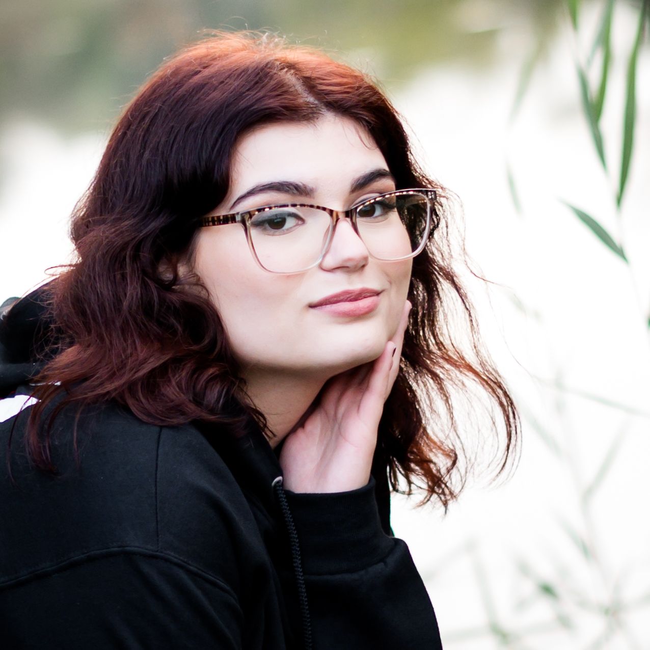 Portrait with glasses against natural background with soft bokeh effect.
