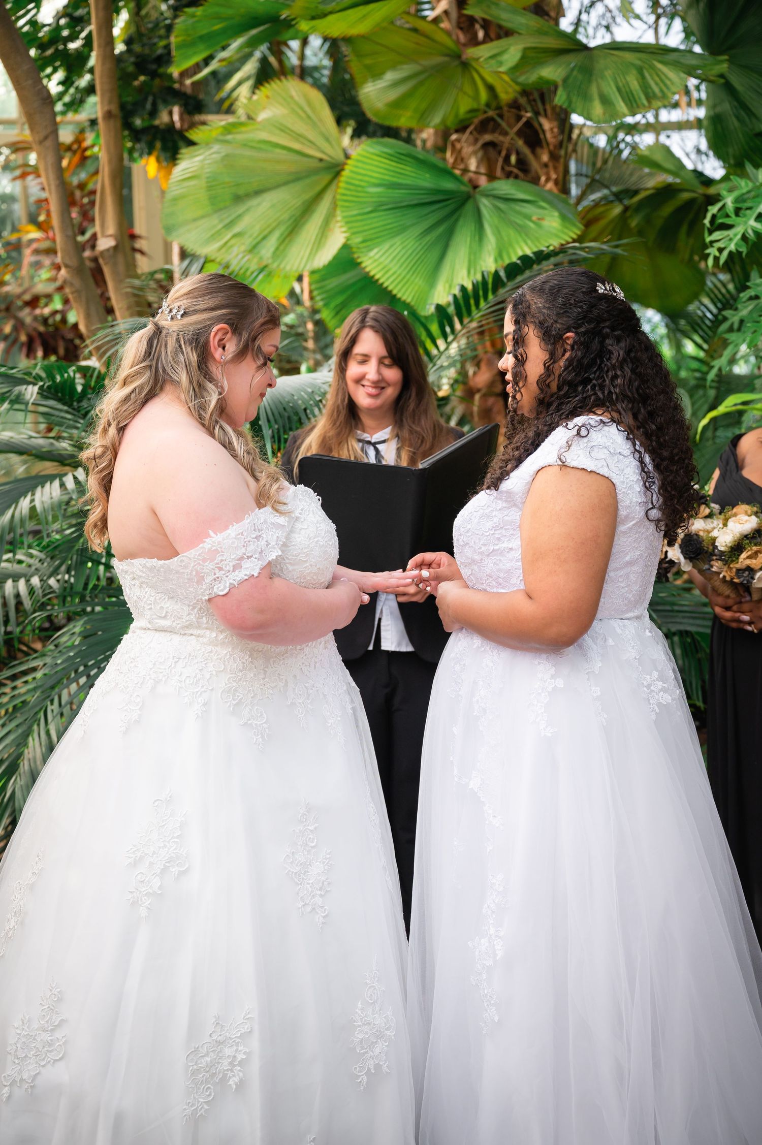 Wedding ceremony in a tropical garden setting with palm fronds and natural decor.