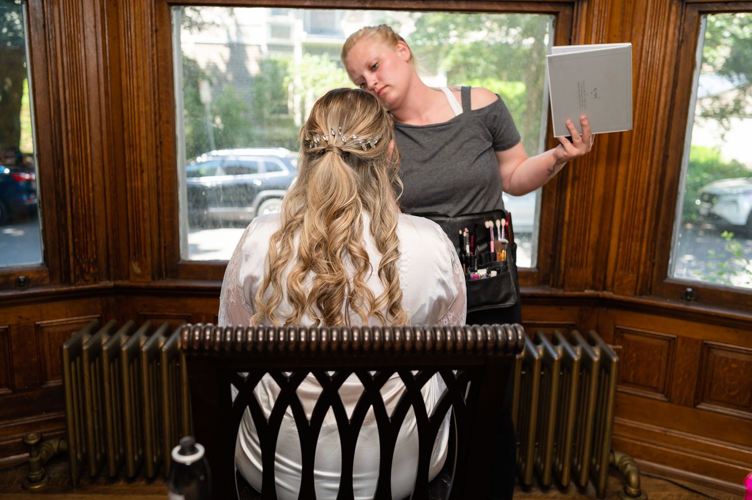 A hair styling session taking place in a wood-paneled room with vintage radiators.