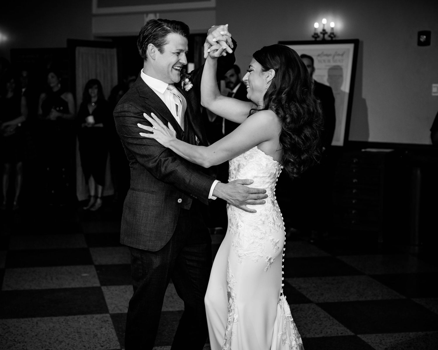 A couple dancing together in formal attire on a black and white checkered floor.