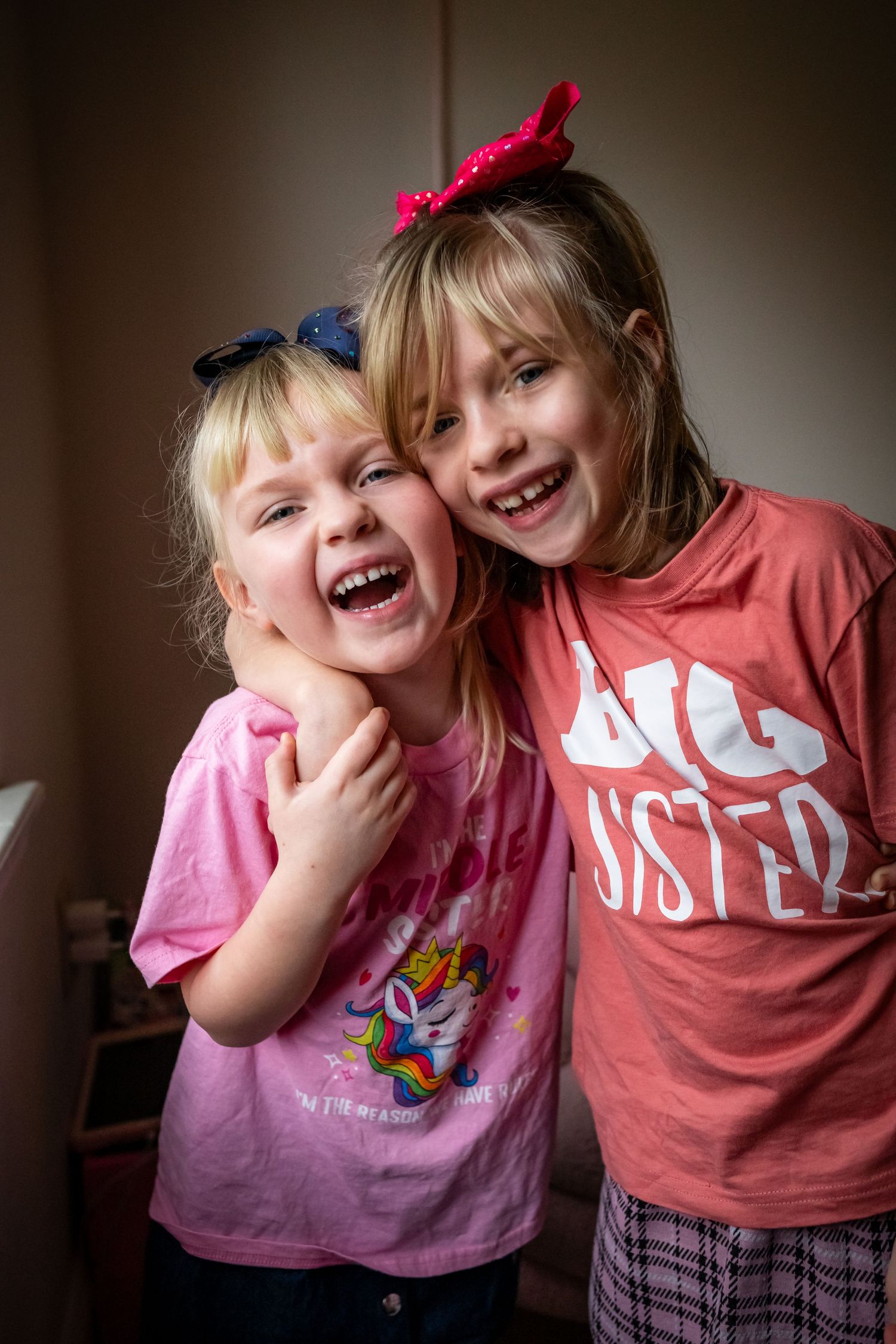Two children in pink and red shirts share joyful laughter together in a sequence of candid moments.