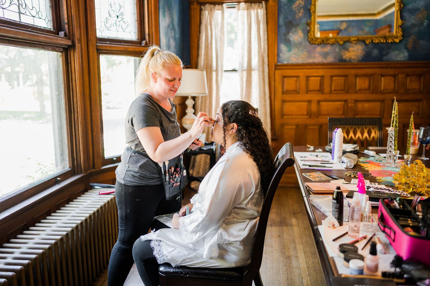 A professional stylist works on hair preparation in a traditional wood-paneled room.