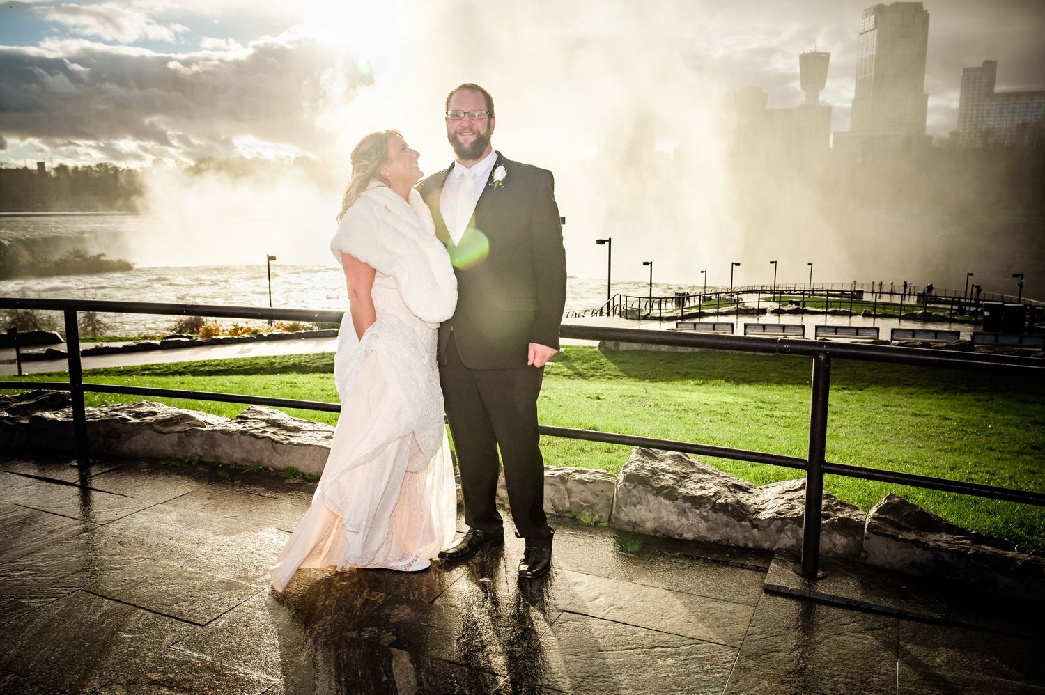 A couple poses for a sunset wedding photo with dramatic waterfront backdrop.