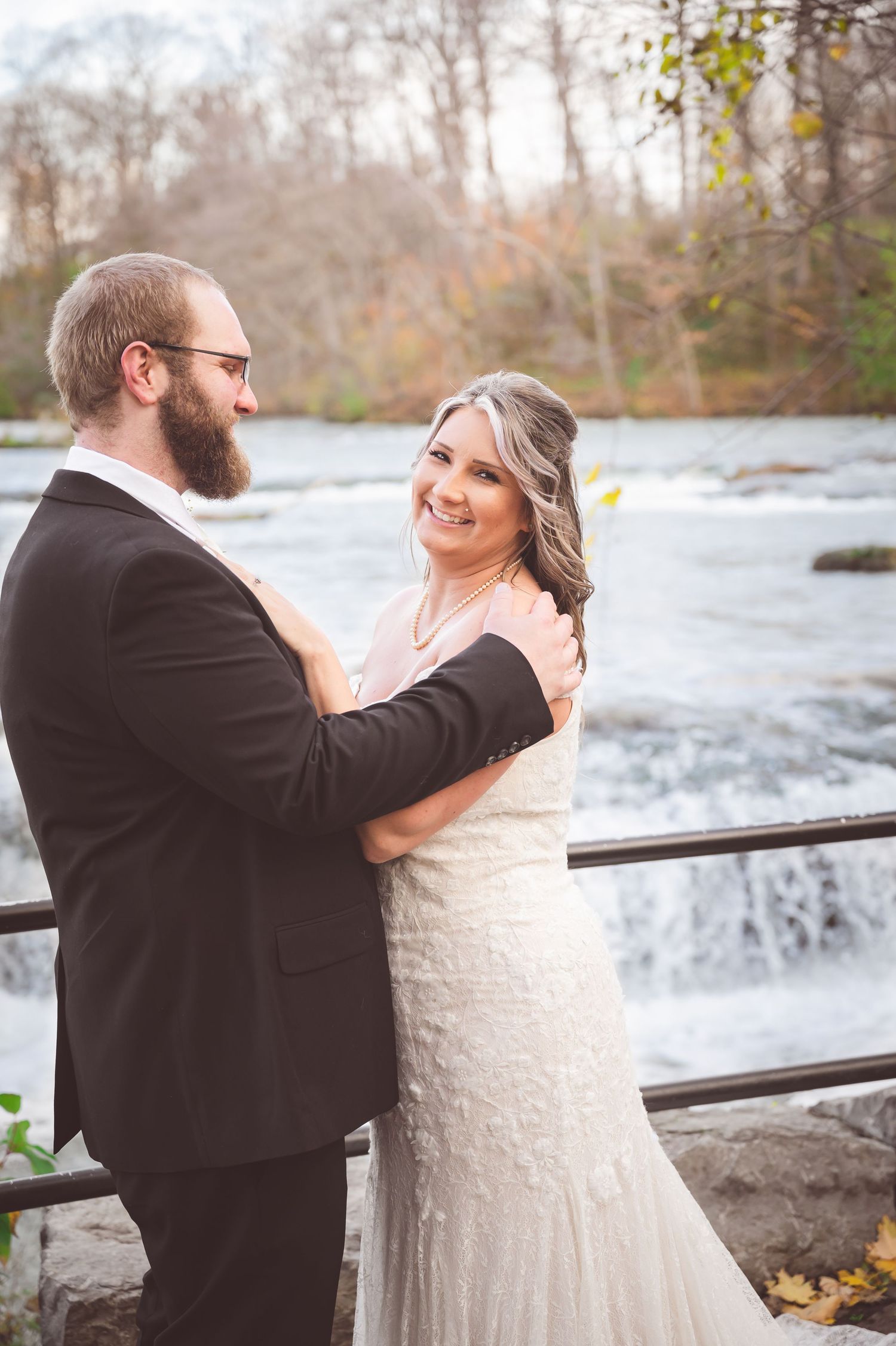 A bride and groom share an intimate moment by a waterfall on their wedding day.