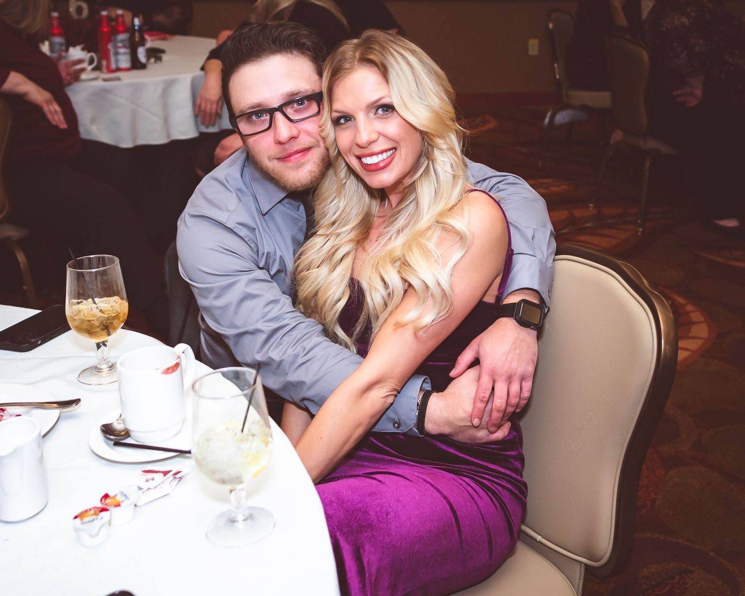 A couple shares an intimate moment at a reception table with drinks.