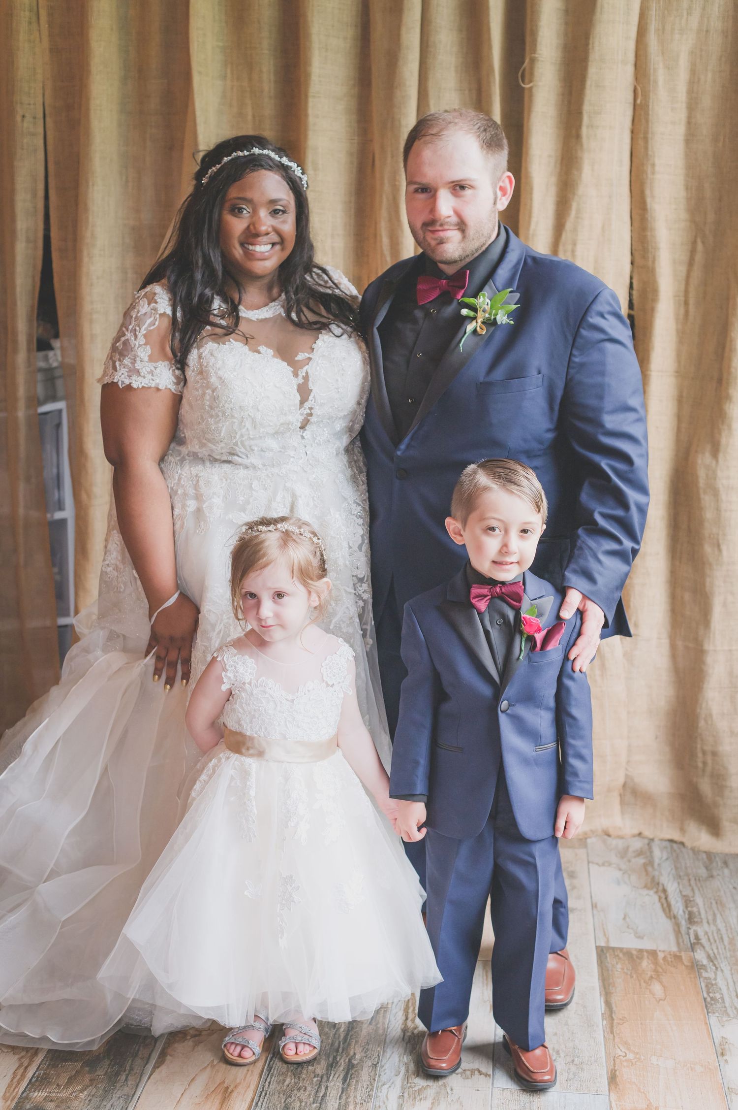 Wedding family portrait shows happy couple with two children in formal attire.