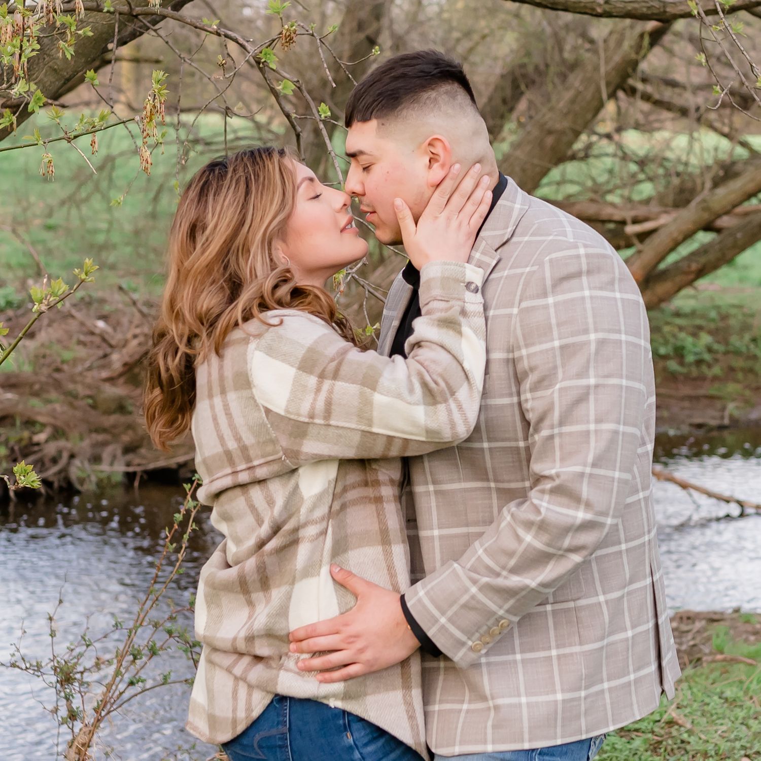 Intimate moment between couple in matching outfits against natural woodland backdrop.