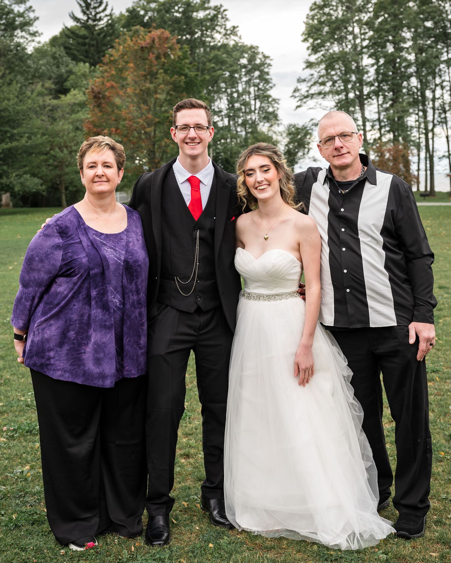 Outdoor family wedding portrait with autumn trees in background.
